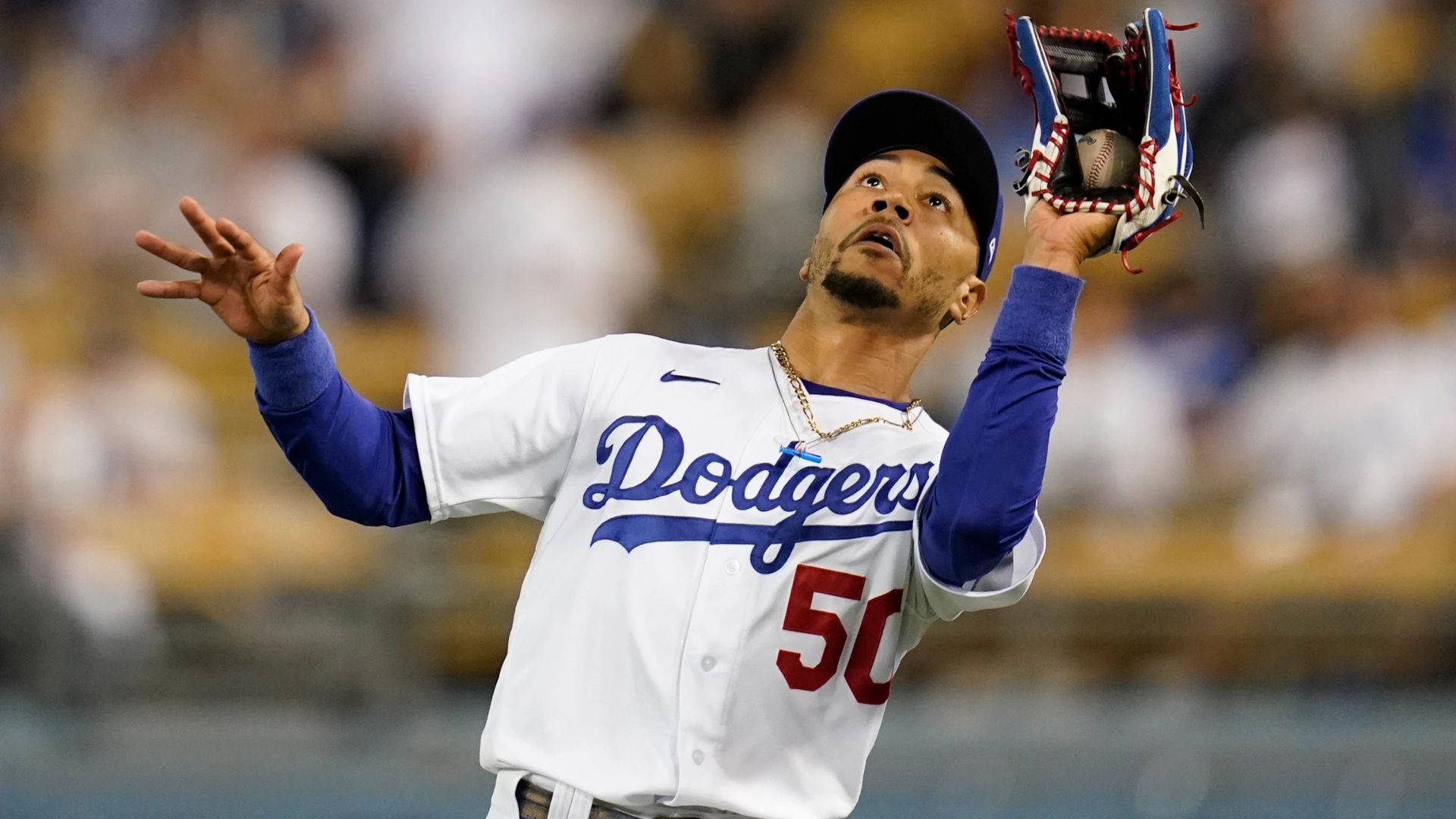 Mookie Betts 桌布 壁紙 — 身穿道奇隊球衣的棒球選手在明亮的燈光下抬頭仰望球場，用手套接住球。