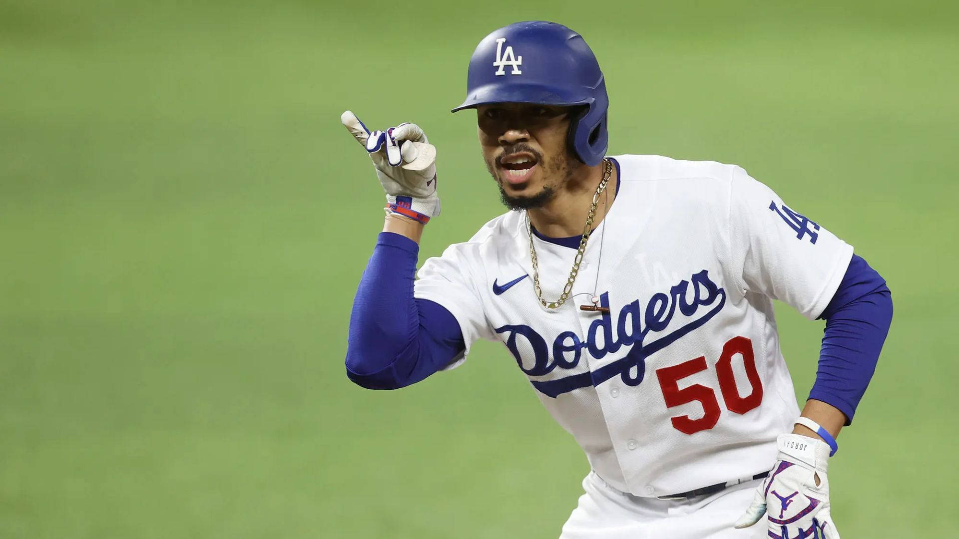 Mookie Betts 桌布 壁紙 — 身穿道奇隊球衣的棒球選手在球場燈光下，於綠色場地上舉起手指慶祝。