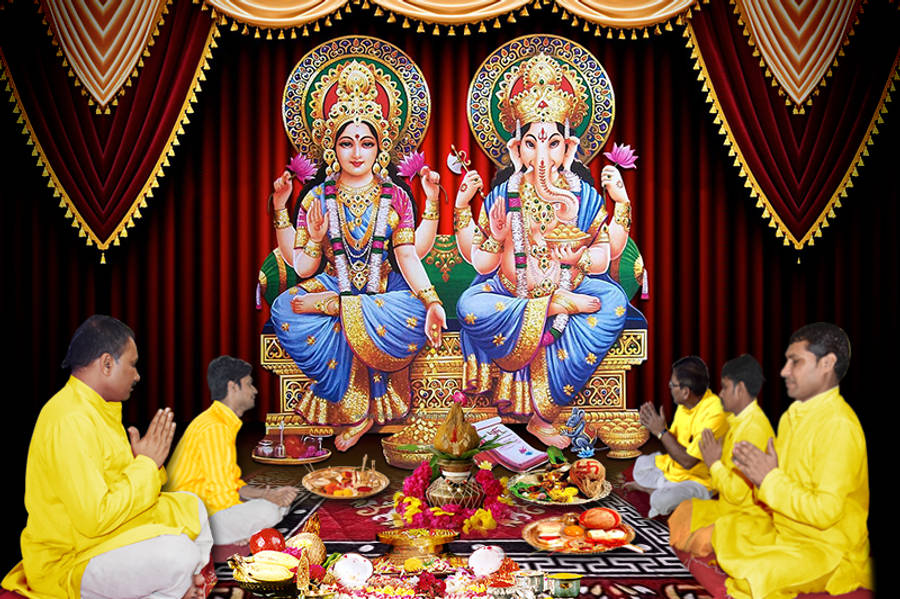 Hindu God 桌布 壁紙 — 身穿黃色長袍的信徒在裝飾著黃金和鮮花的印度教神祇拉克什米和象頭神的大型壁畫前祈禱。