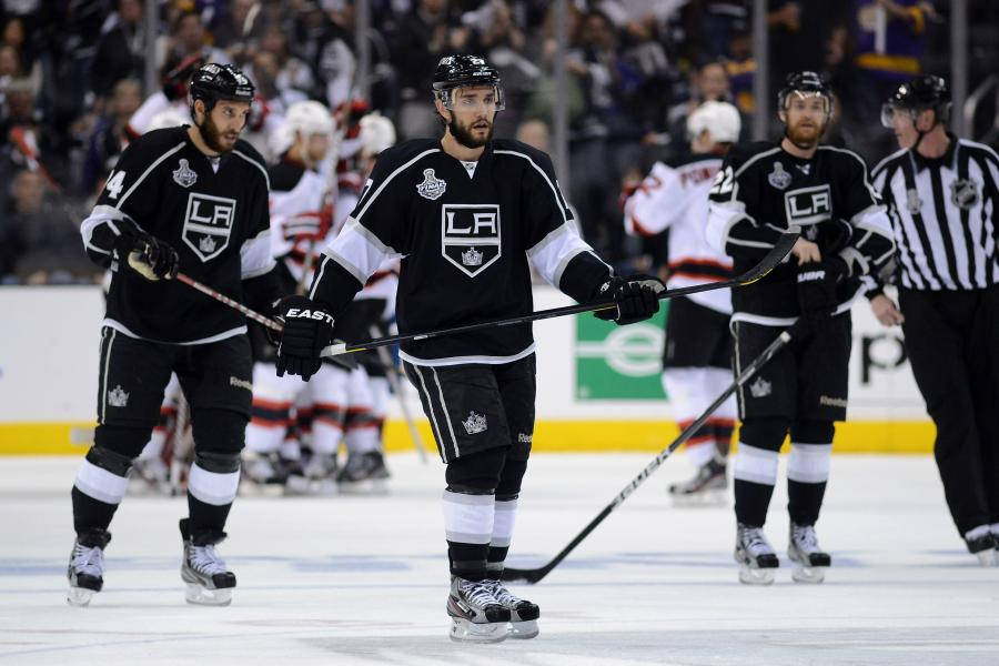 Los Angeles Kings 桌布 壁紙 — 身穿黑色LA Kings球衣的冰球運動員在比賽中溜冰，背景有裁判和觀眾。