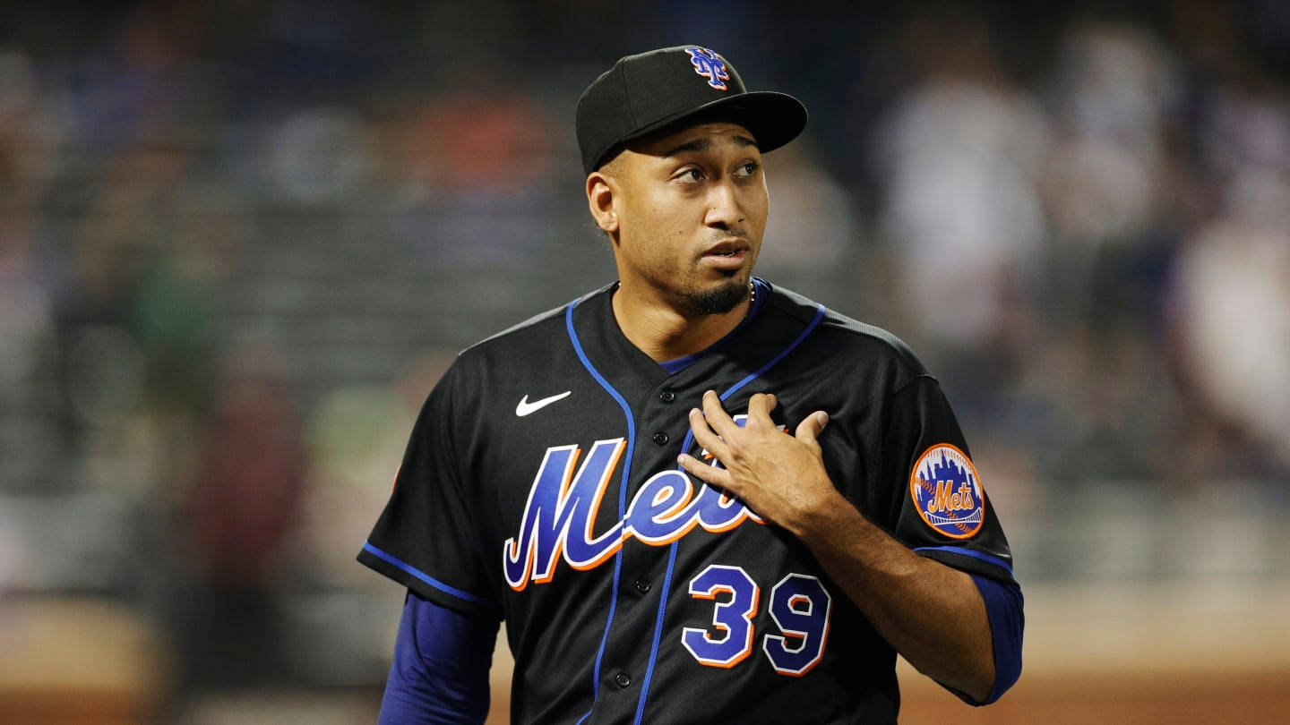MLB Players 桌布 壁紙 — 身穿黑色Mets球衣、號碼39的棒球選手在球場燈光下比賽時將手放在心口上。