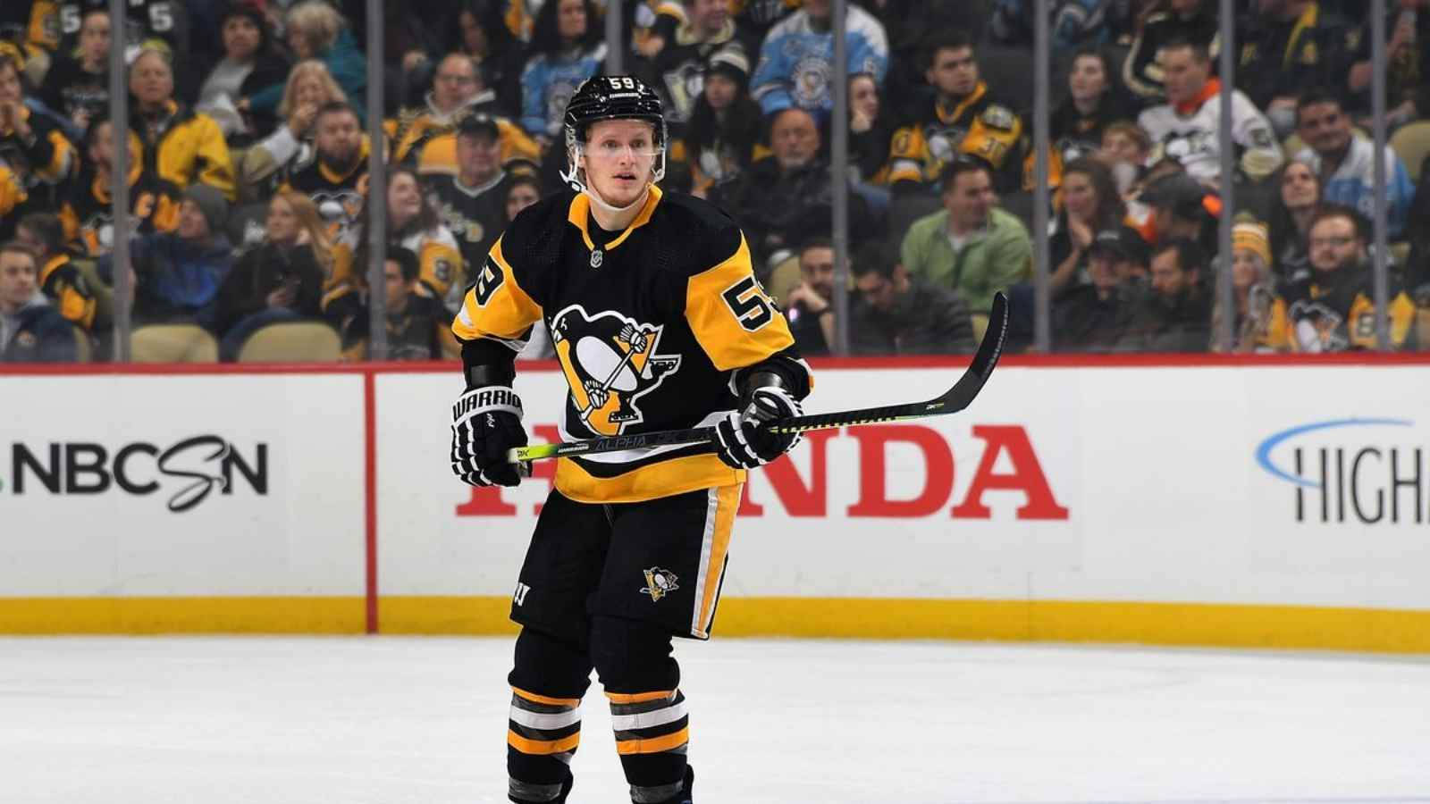 hockey 桌布 壁紙 — 身穿黑色和金色制服的冰球球員站在冰上，手持球棍，背景有觀眾。