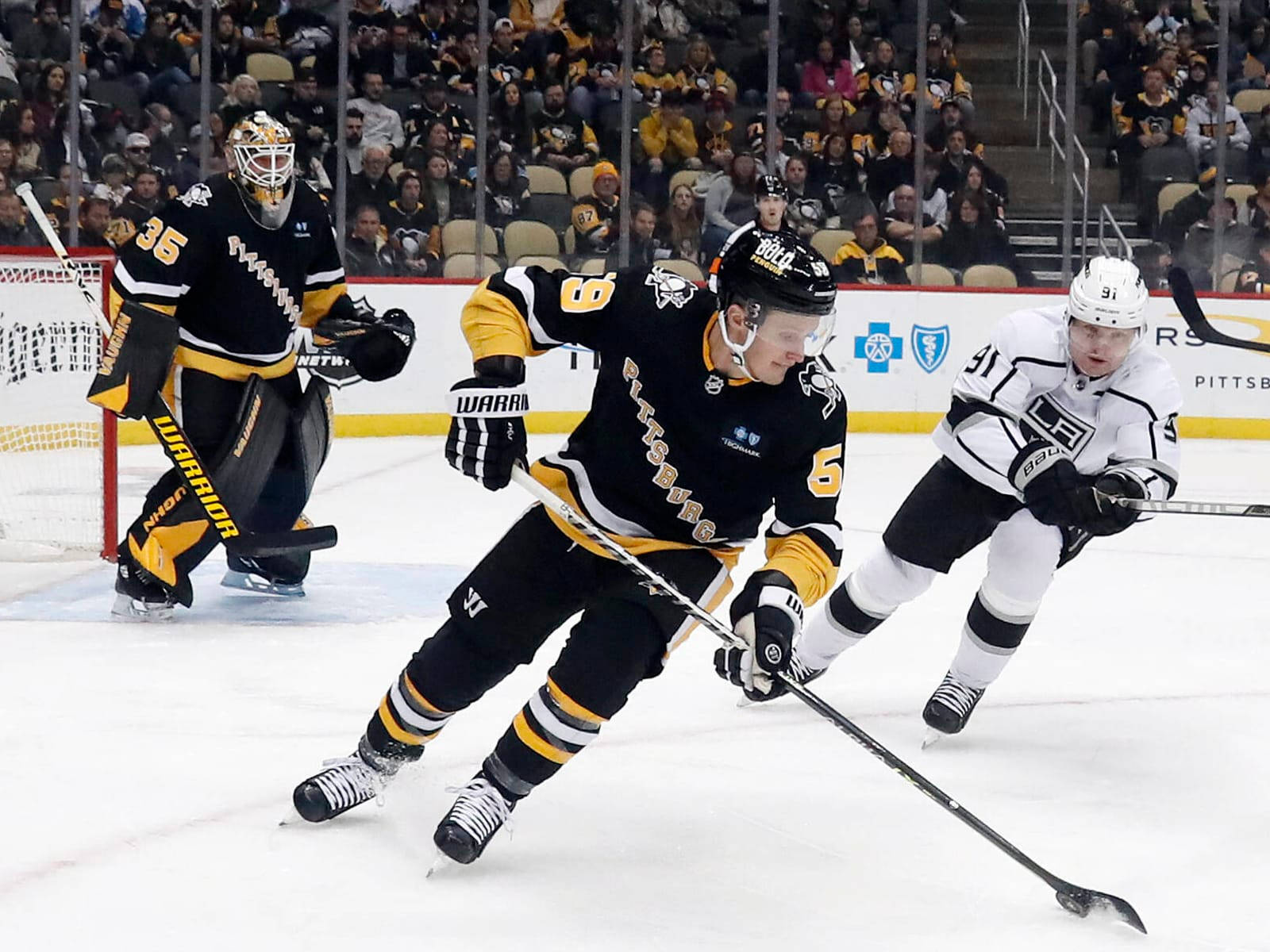 hockey 桌布 壁紙 — 身穿黑色和金色球衣的冰球運動員在冰上爭奪控球權，觀眾專注觀看。