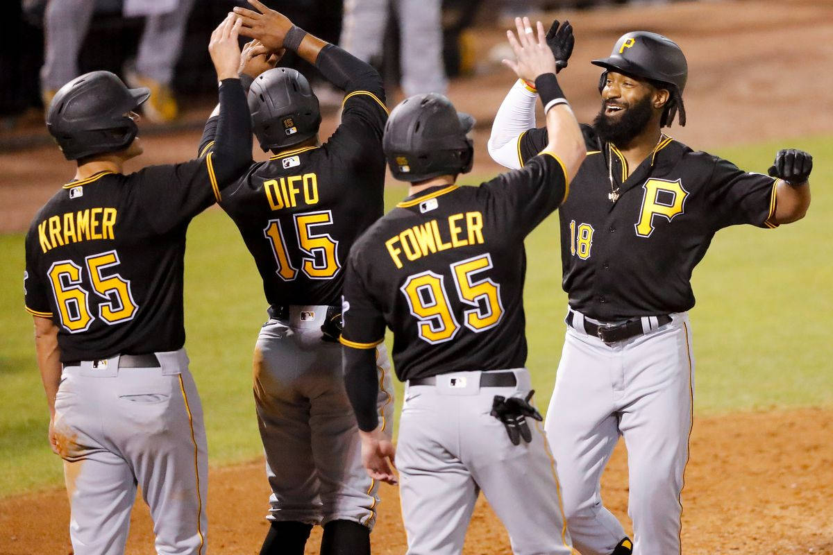 Pittsburgh Pirates 桌布 壁紙 — 身穿黑色和金色球衣的棒球運動員在球場燈光下的泥地球場上擊掌慶祝。