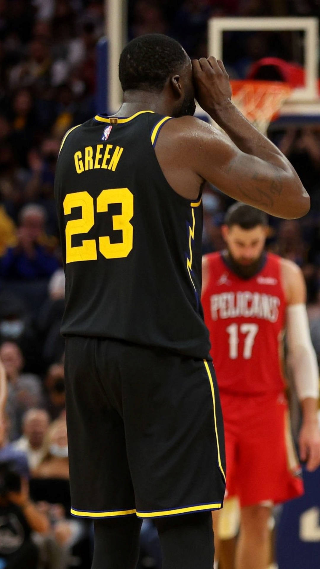 Draymond Green 桌布 壁紙 — 身穿黑色和黃色球衣的籃球運動員格林在比賽期間於擁擠的場館中雙手抱頭站立。