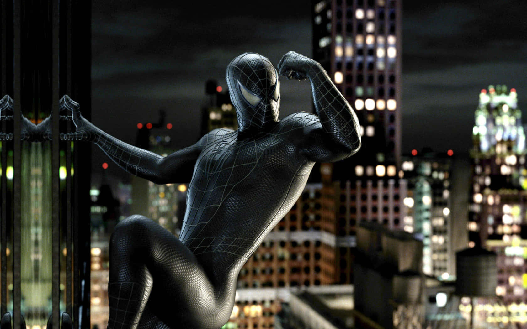 Spider Man 3 桌布 壁紙 — 身穿黑色戰衣的蜘蛛俠在摩天大樓邊緣以英雄姿態擺出姿勢，背景是夜晚閃爍的城市天際線。