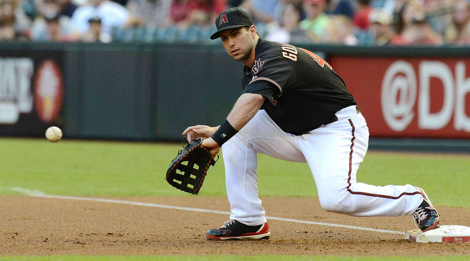 Paul Goldschmidt 桌布 壁紙 — 身穿黑色球衣的棒球選手在日間比賽中低身飛撲接住一壘附近的滾地球。