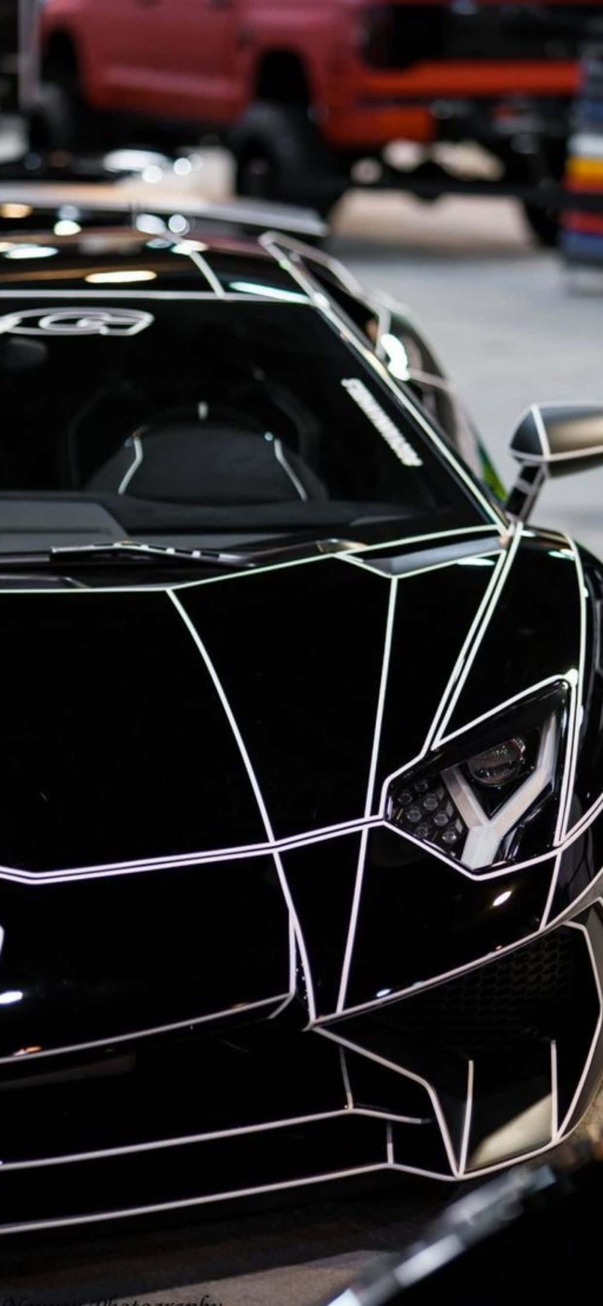 Lamborghini Phone 桌布 壁紙 — 車庫中黑色藍寶堅尼的近距離特寫，發光的白色幾何線條突顯其銳利的角度設計。