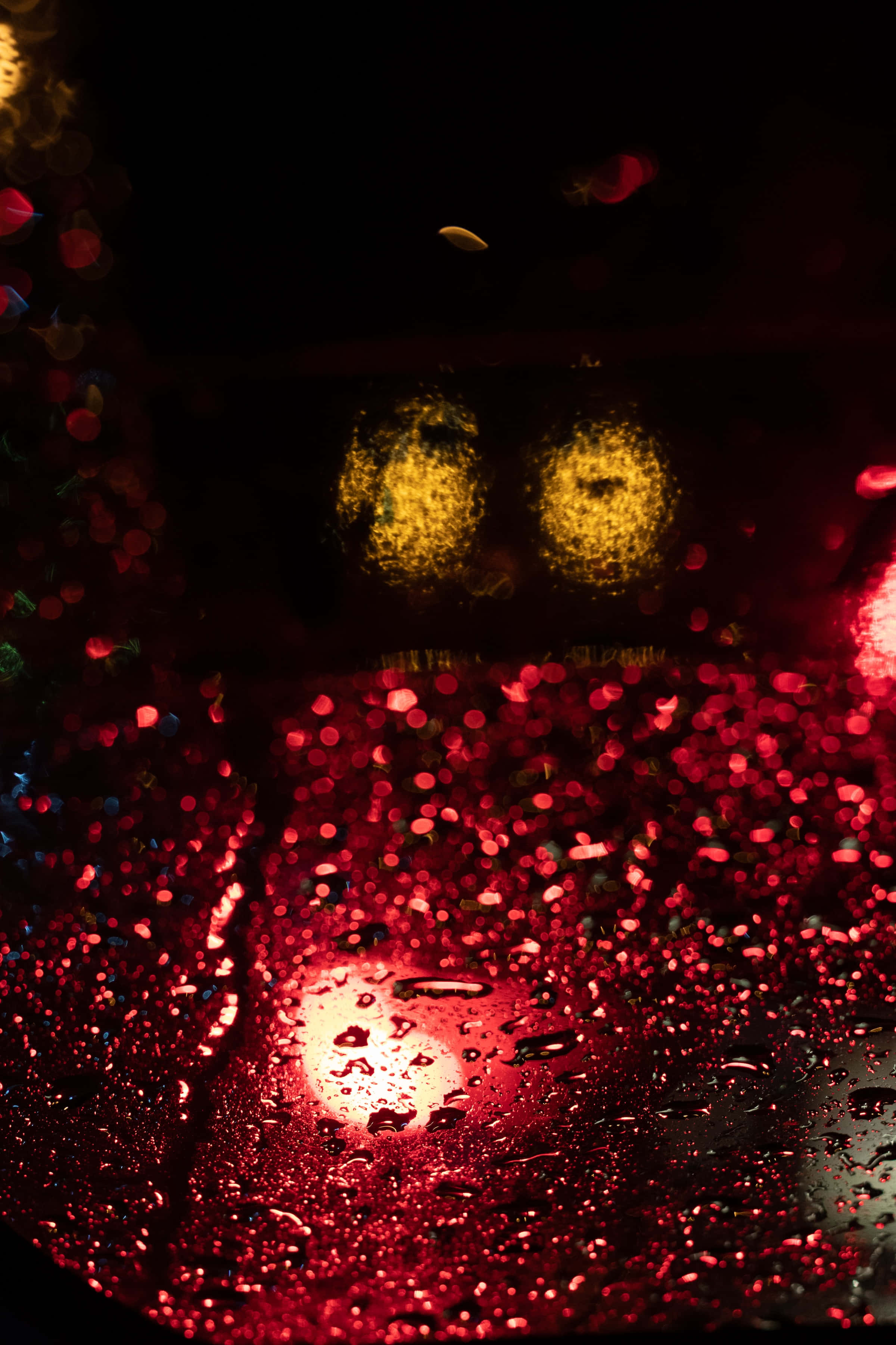 Red Glitter 桌布 壁紙 — 車窗上的雨滴將鮮豔的紅色和黃色城市燈光模糊成夜間發光散景。