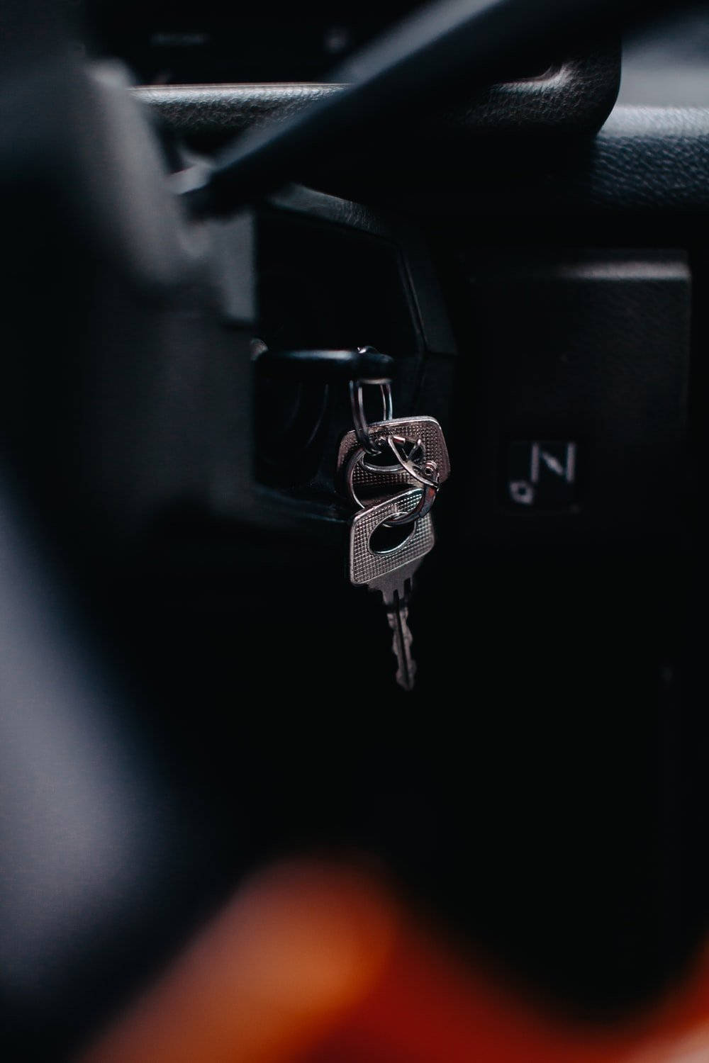 driving 桌布 壁紙 — 車鑰匙掛在黑暗車廂內的點火開關上的特寫，下方有模糊的橙色光芒。