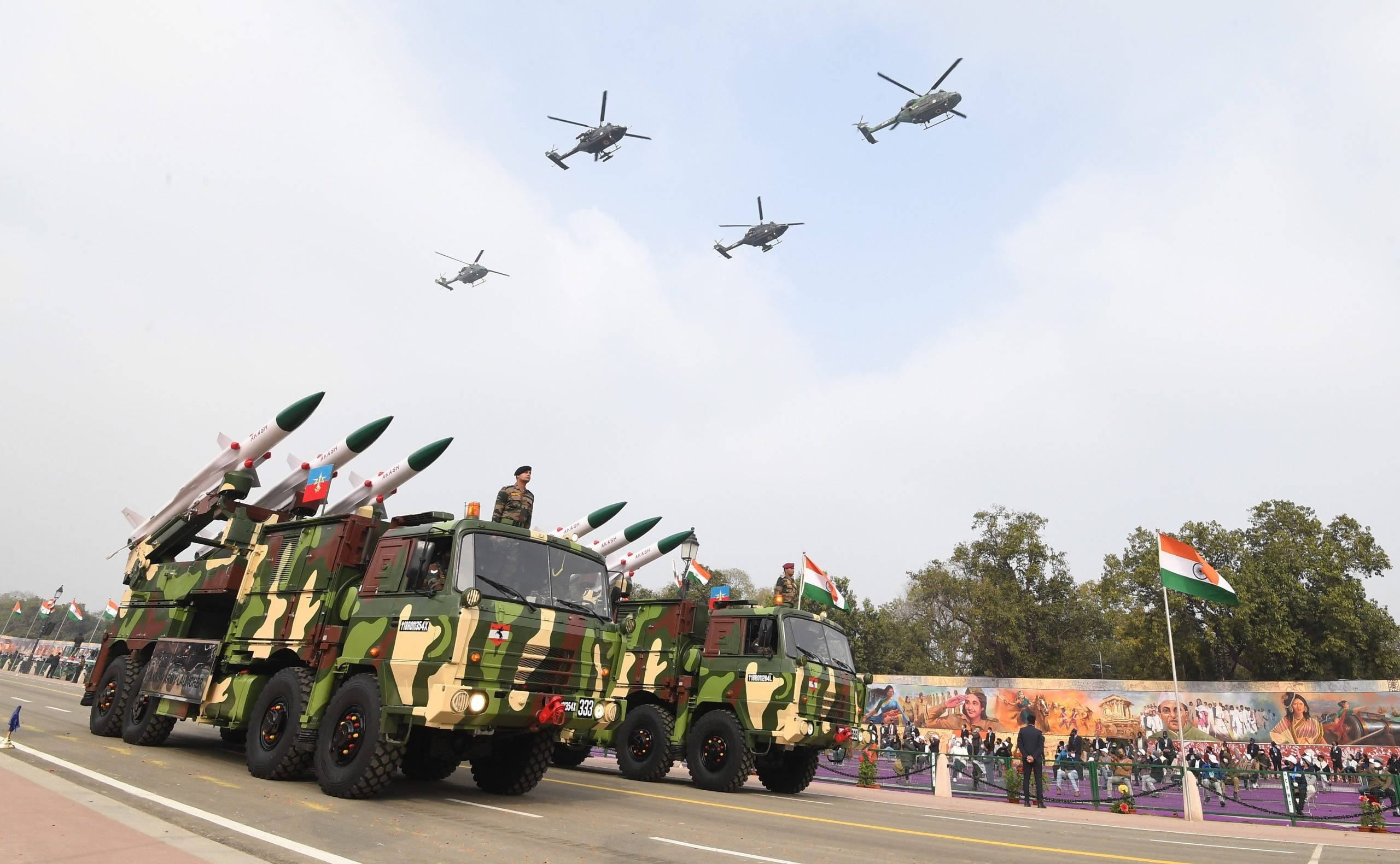 印度軍隊 桌布 壁紙 — 軍用卡車載著導彈在街上遊行，直升機在頭頂飛過，慶祝國慶。