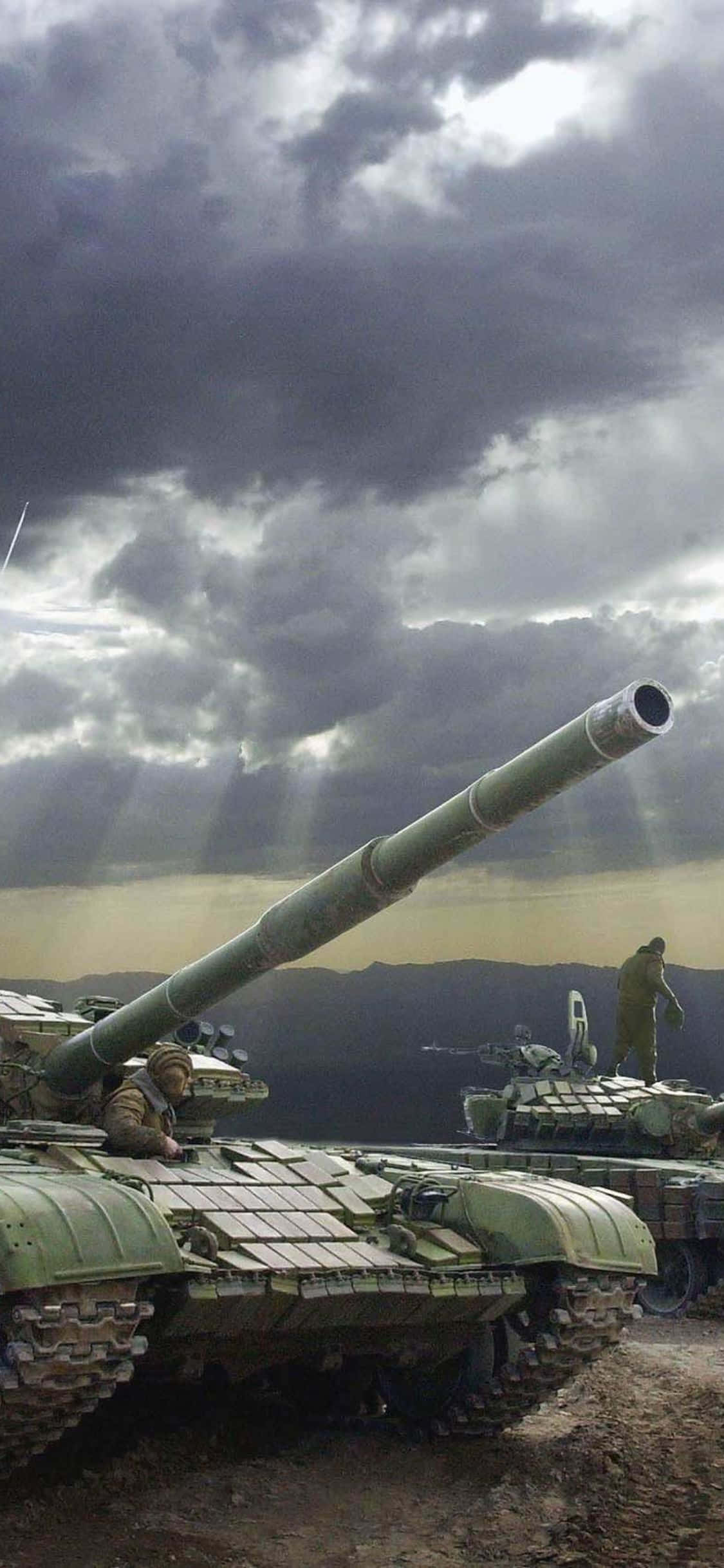 iPhone Xs Tanks 桌布 壁紙 — 軍用坦克矗立在戲劇性的暴風雨天空下，陽光穿透烏雲。