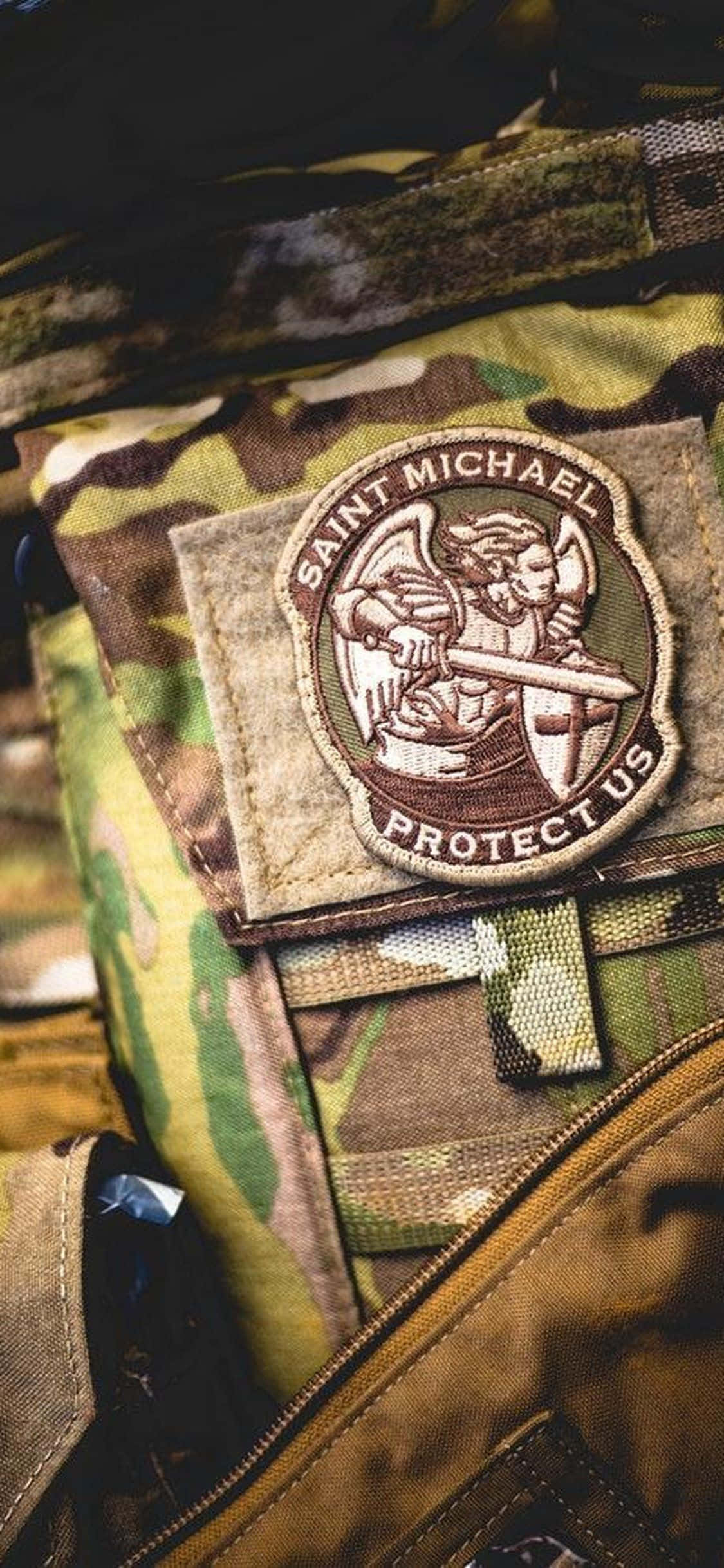 軍事動圖 桌布 壁紙 — 軍用迷彩裝備上聖米迦勒徽章的近距離特寫，帶有精緻刺繡和紋理布料。