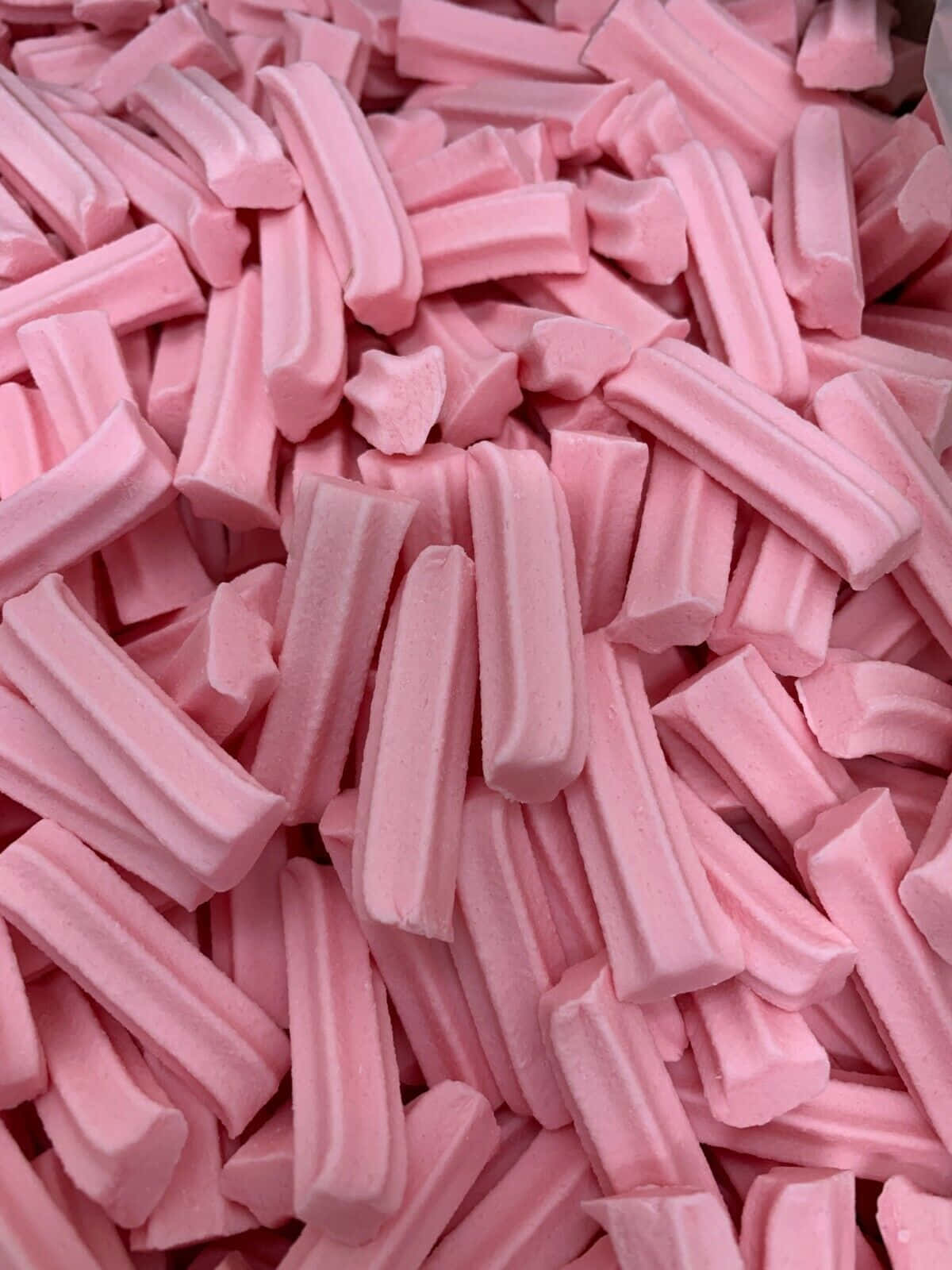 Pink Candy 桌布 壁紙 — 軟粉紅色甘草棒堆成甜糖果堆的特寫，帶有柔和陰影。