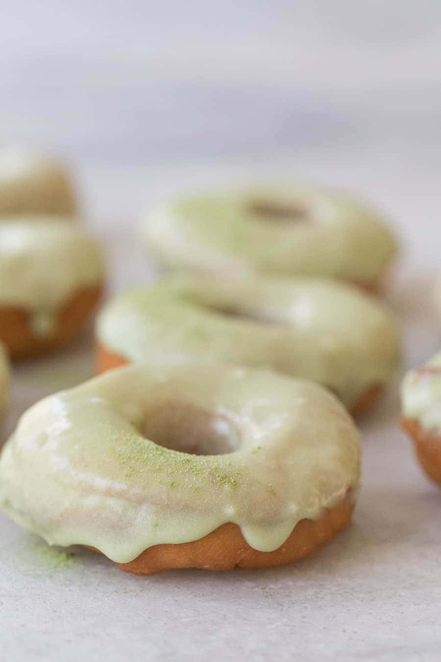 Donut 桌布 壁紙 — 軟糖霜甜甜圈撒上綠色粉末，放在淺景深的淺色表面上。