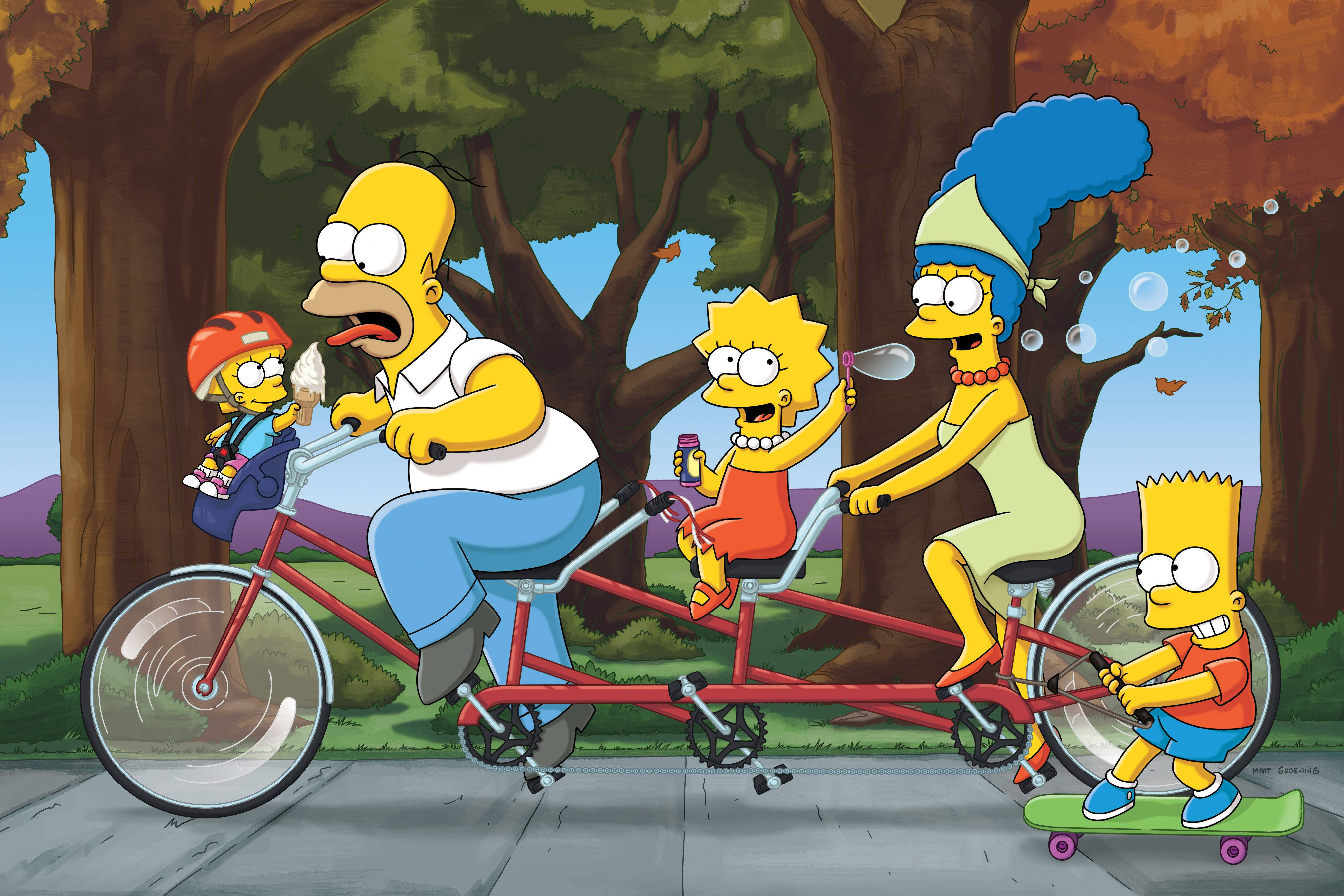 marge 桌布 壁紙 — 辛普森一家騎著紅色雙人自行車穿過森林，巴特在後面滑滑板，所有人都在秋樹下微笑。