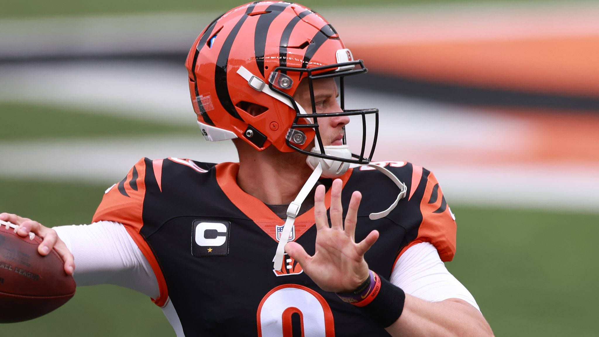 Joe Burrow 桌布 壁紙 — 辛辛那提猛虎隊的四分衛身穿黑色和橙色制服，準備在綠色場地上擲出橄欖球。