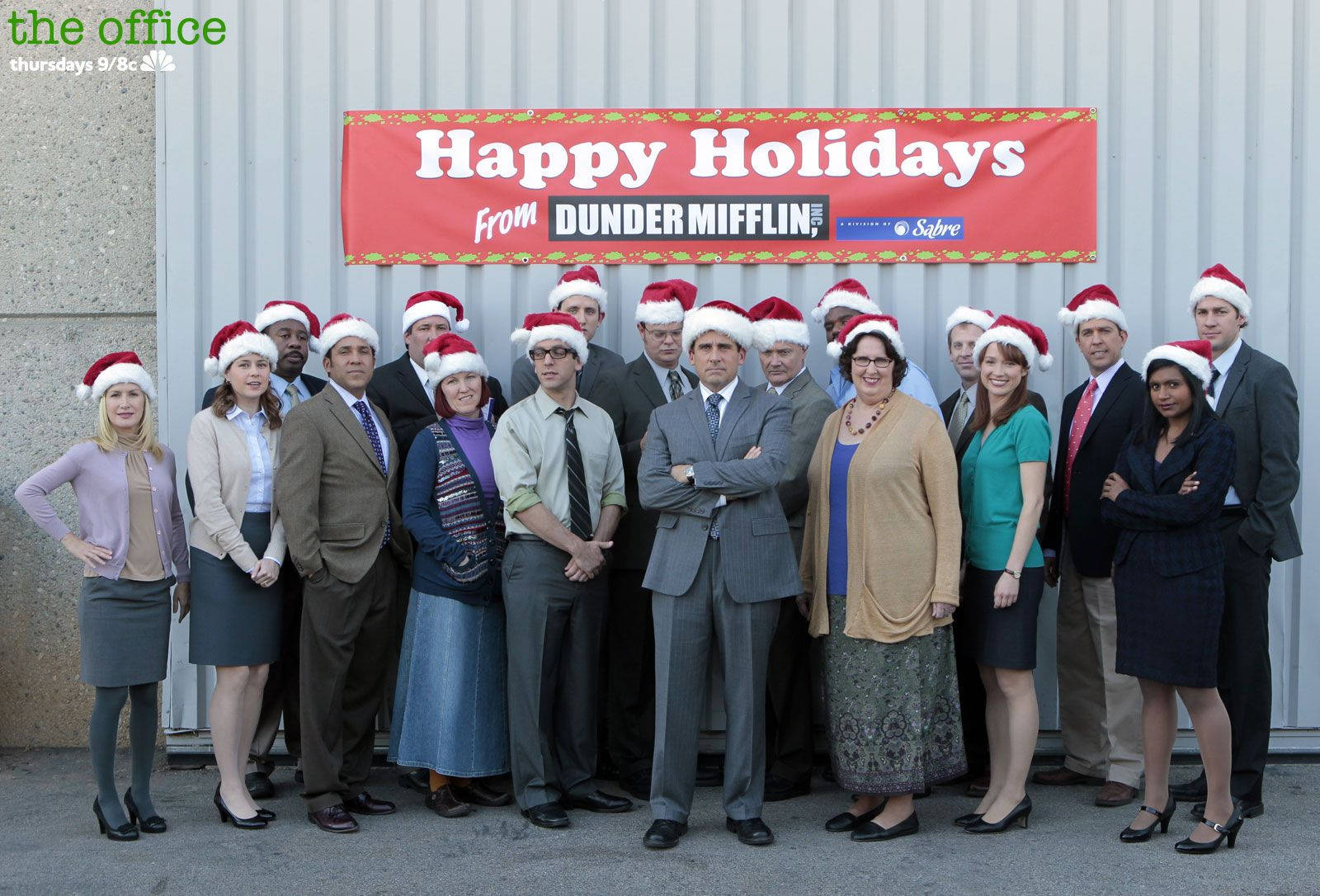辦公室 桌布 壁紙 — 《辦公室》演員們戴著節日聖誕帽，在紅色「Dunder Mifflin 祝您節日快樂」橫幅下擺姿勢。