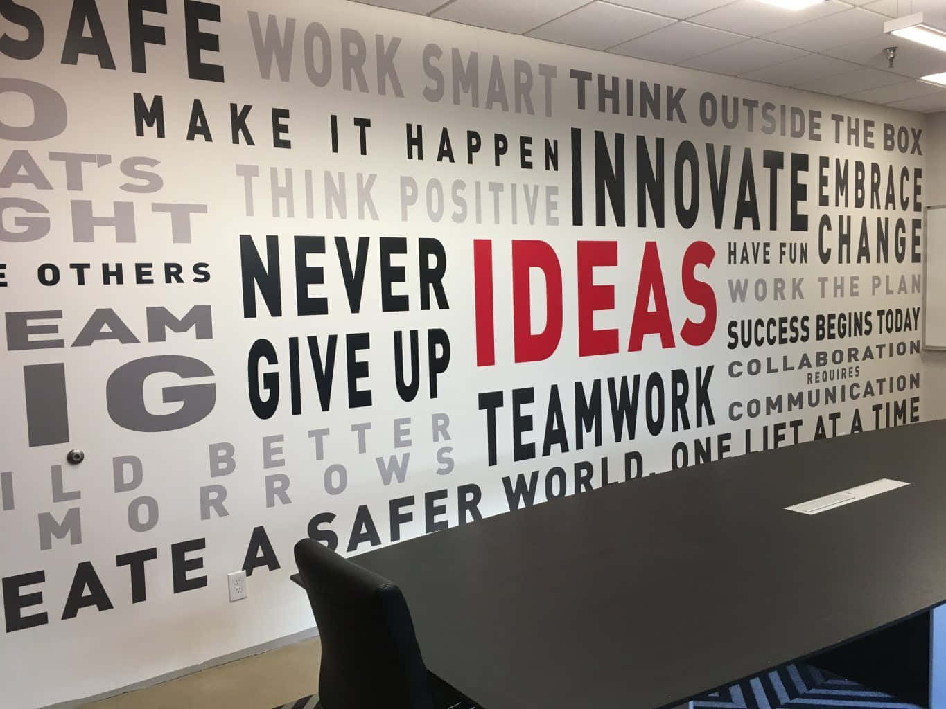 辦公室 桌布 壁紙 — 辦公室內的一面勵志詞語牆，上面有「IDEAS」紅色字樣和「TEAMWORK」粗體黑色字母等短語。