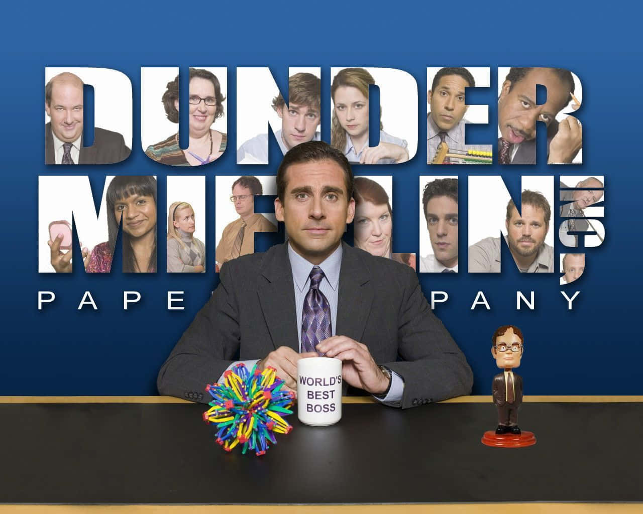 Michael Scott 桌布 壁紙 — 辦公室職員坐在辦公桌前，手持馬克杯和彩色減壓球，身後標誌中有Dunder Mifflin的角色。