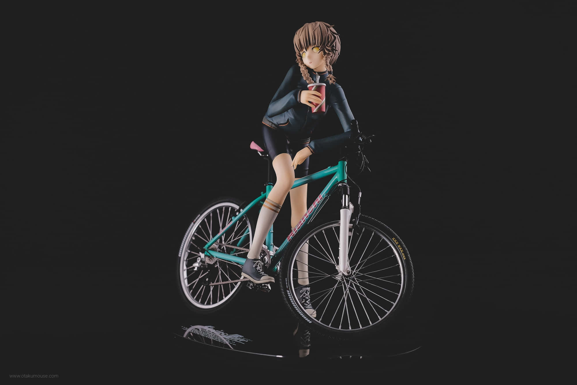 Suzuha Amane 桌布 壁紙 — 辮子動漫女孩公仔坐在青綠色腳踏車上，手持紅色杯子，背景為黑色。