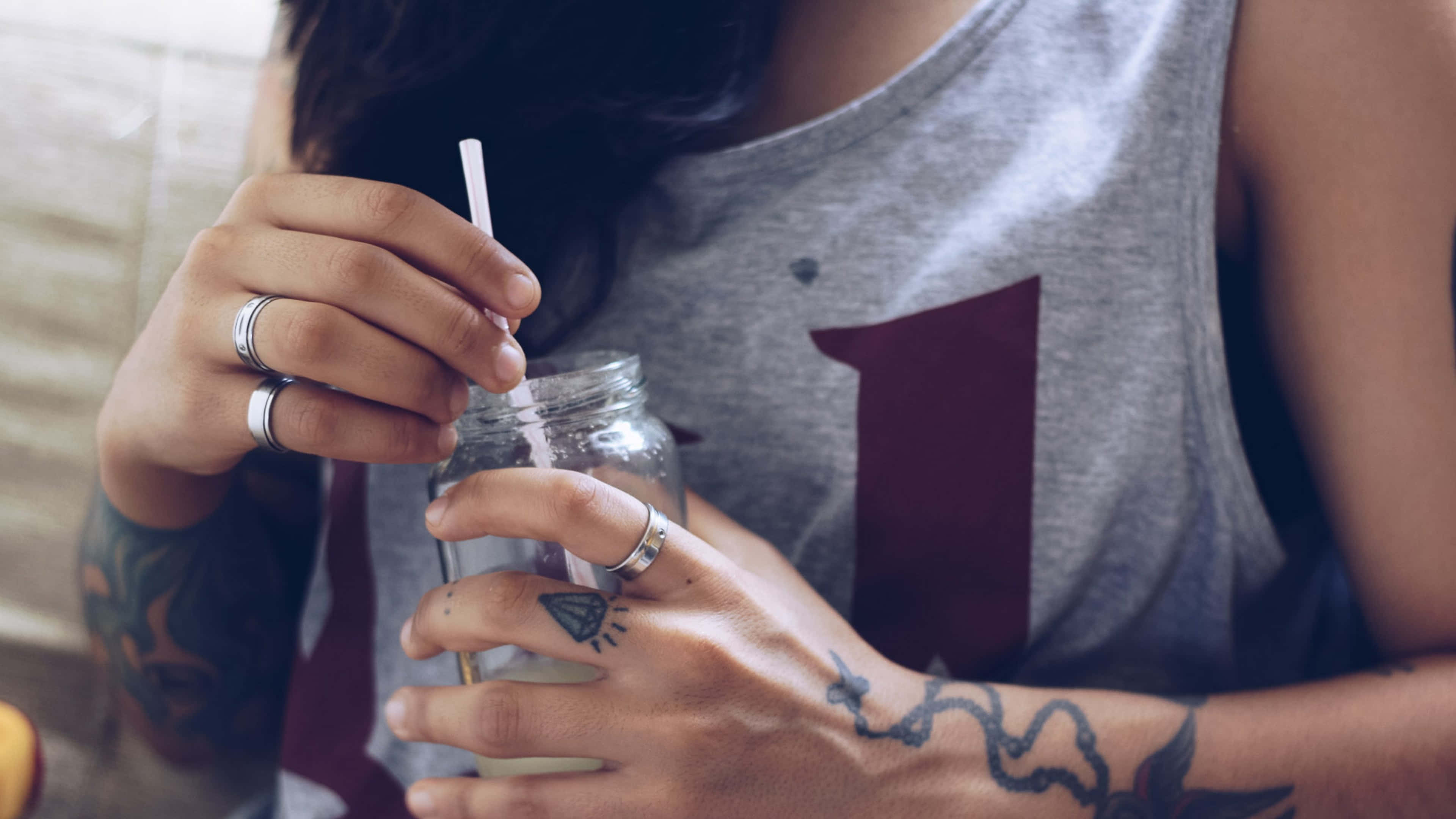 藝術 桌布 壁紙 — 近距離拍攝一位有刺青的人手持帶有吸管的玻璃罐。