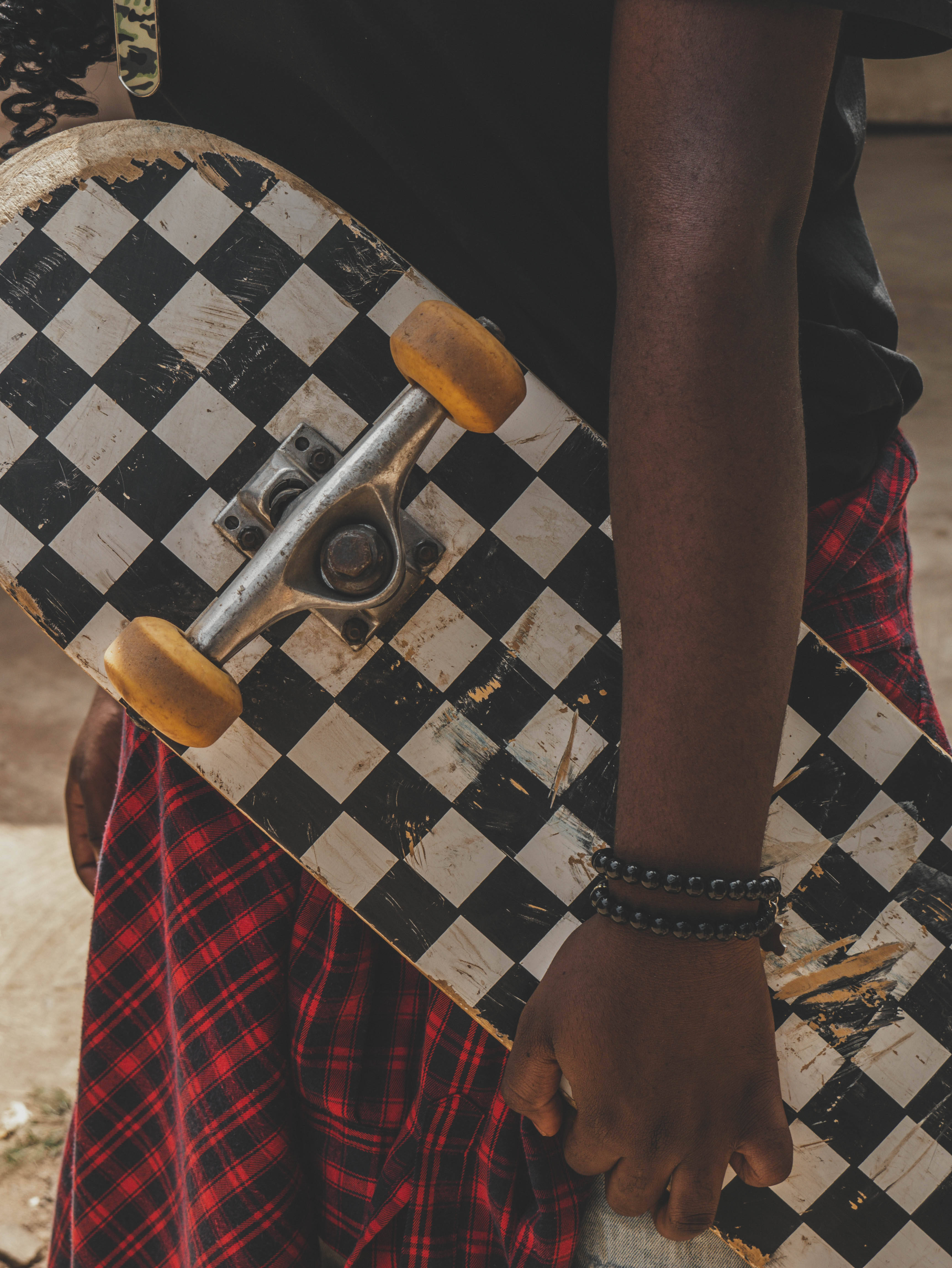 Checkered 桌布 壁紙 — 近距離拍攝一個人手持磨損的黑白格紋滑板，配黃色輪子。