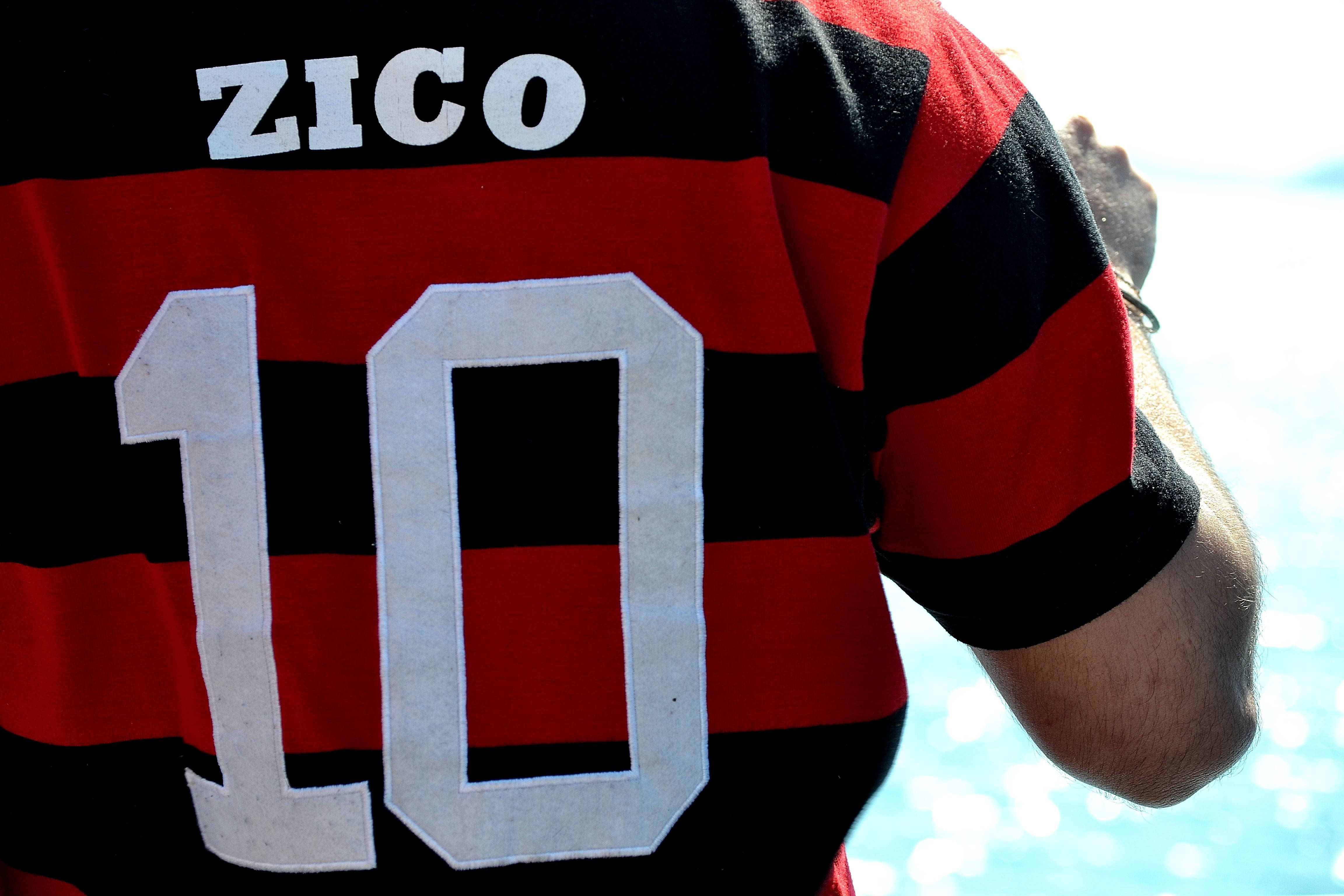 flamengo fc 桌布 壁紙 — 近距離拍攝一個人穿著紅黑條紋足球球衣，上面有白色的「ZICO」和號碼「10」，站在水邊。