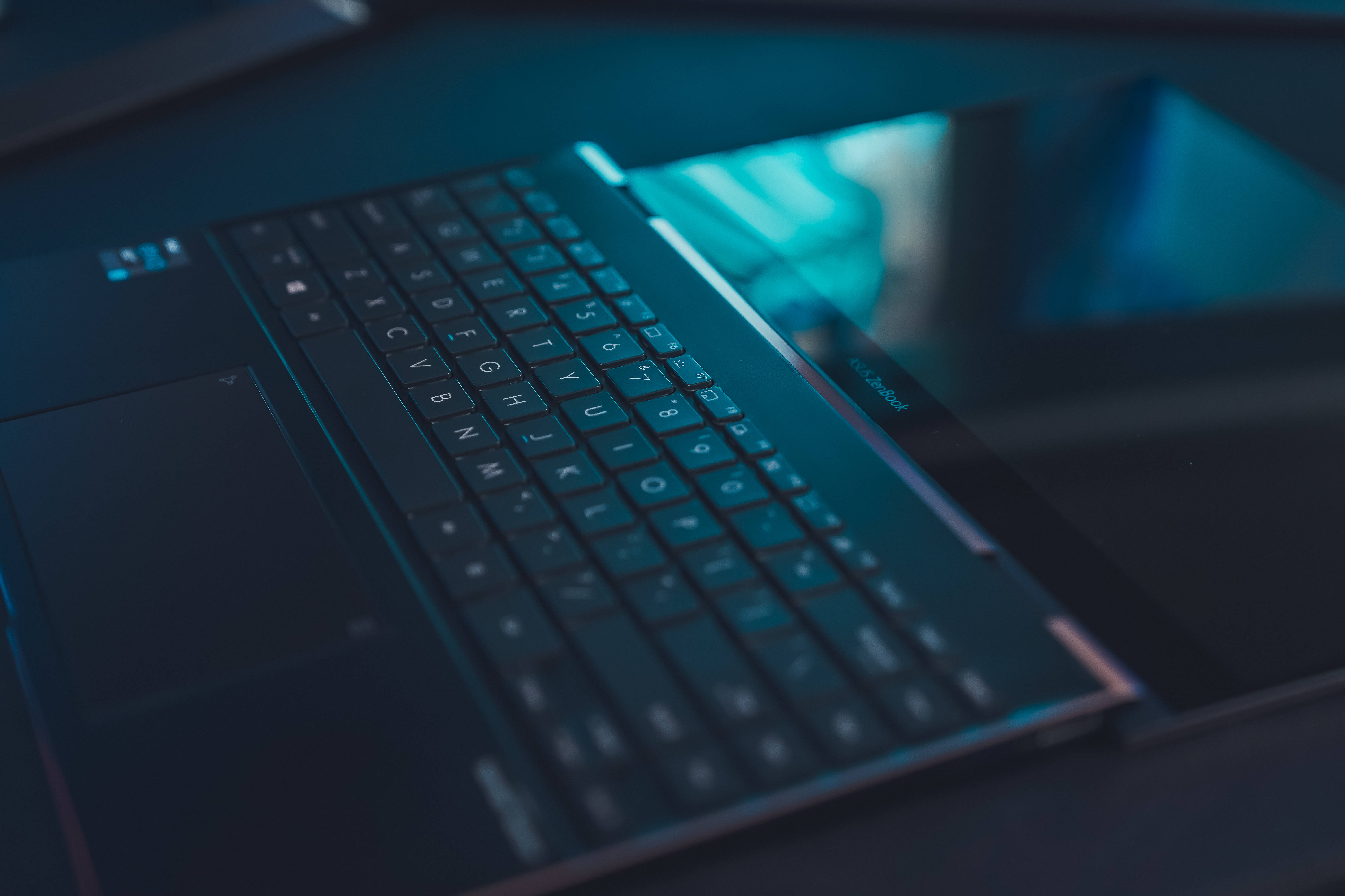 Rog 桌布 壁紙 — 近距離拍攝一個時尚筆記型電腦鍵盤，沐浴在冷藍光中，帶有模糊的螢幕反射。