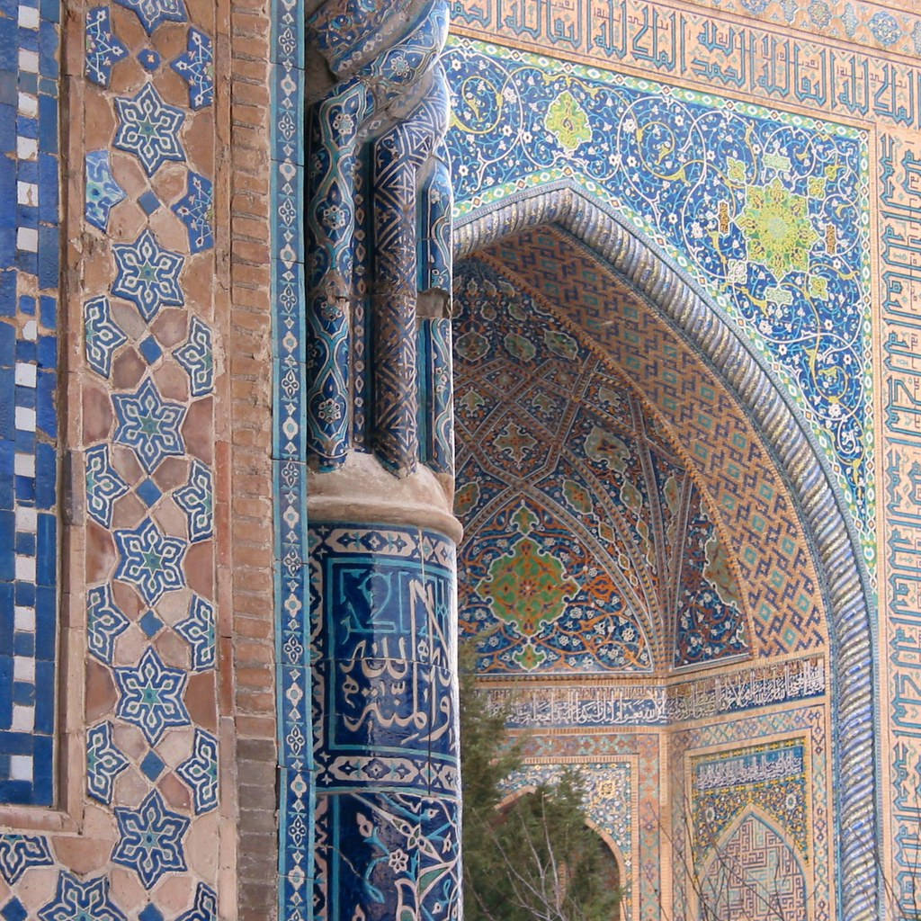 Uzbekistan 桌布 壁紙 — 近距離拍攝一個華麗的伊斯蘭拱門，飾有複雜的藍色瓷磚幾何圖案和阿拉伯書法。