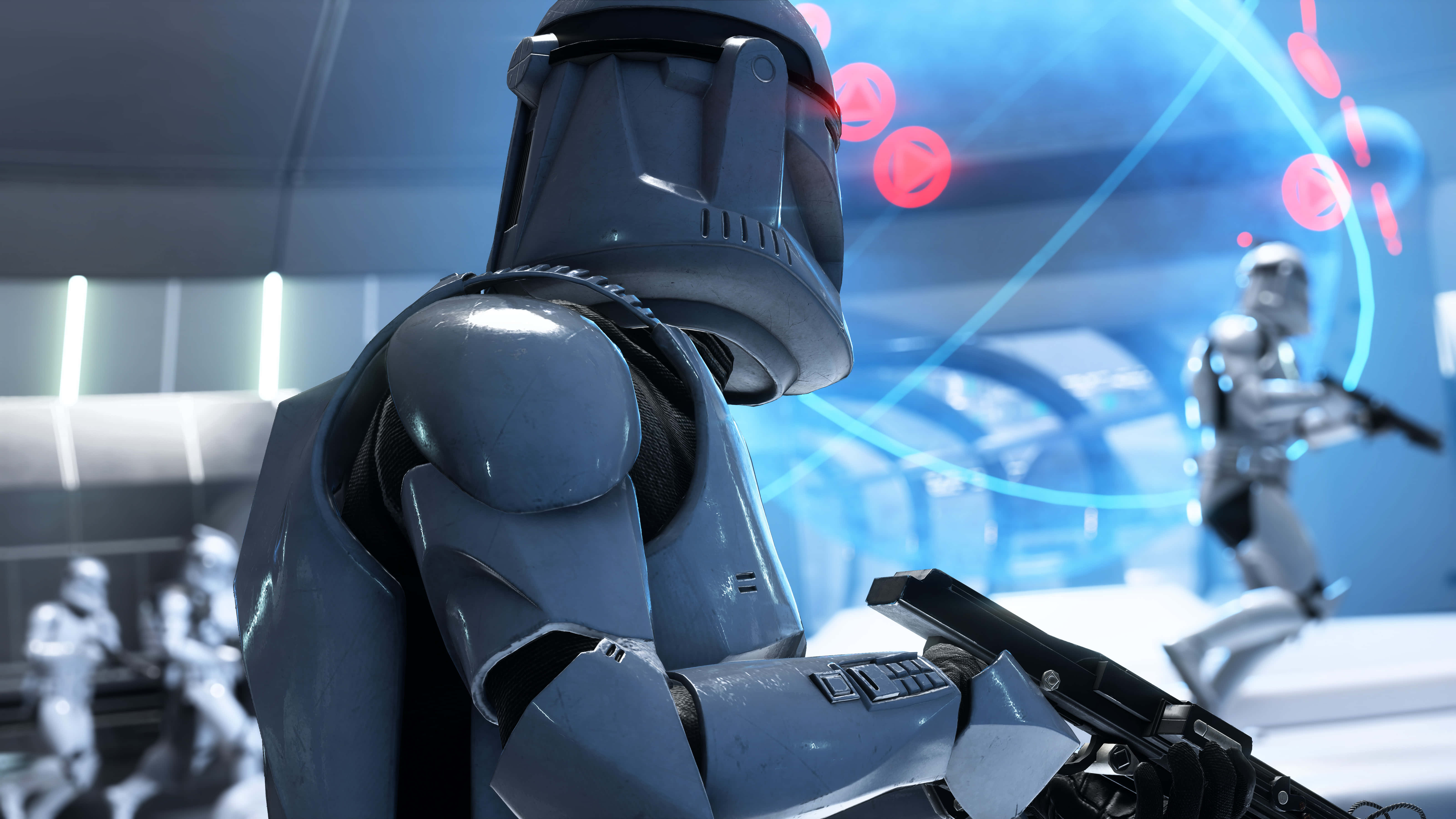 Star Wars Games 桌布 壁紙 — 近距離拍攝一名身穿灰色裝甲的複製人突擊隊員，在未來感藍色燈光的指揮中心手持爆能槍，周圍有全息顯示屏。