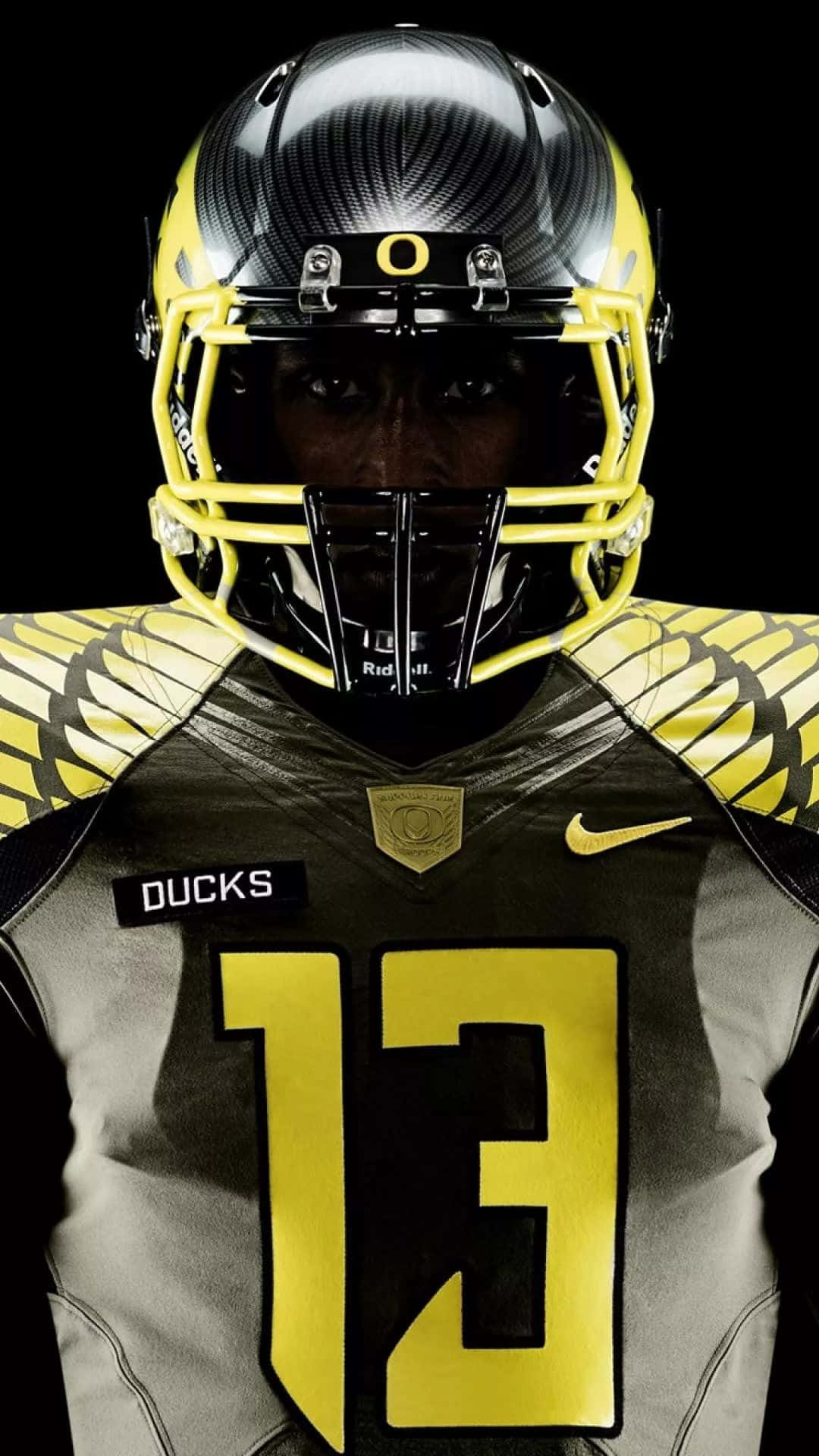 Oregon Ducks 桌布 壁紙 — 近距離拍攝一名身穿黑黃色俄勒岡鴨隊球衣、號碼13的美式足球員，背景為黑色。