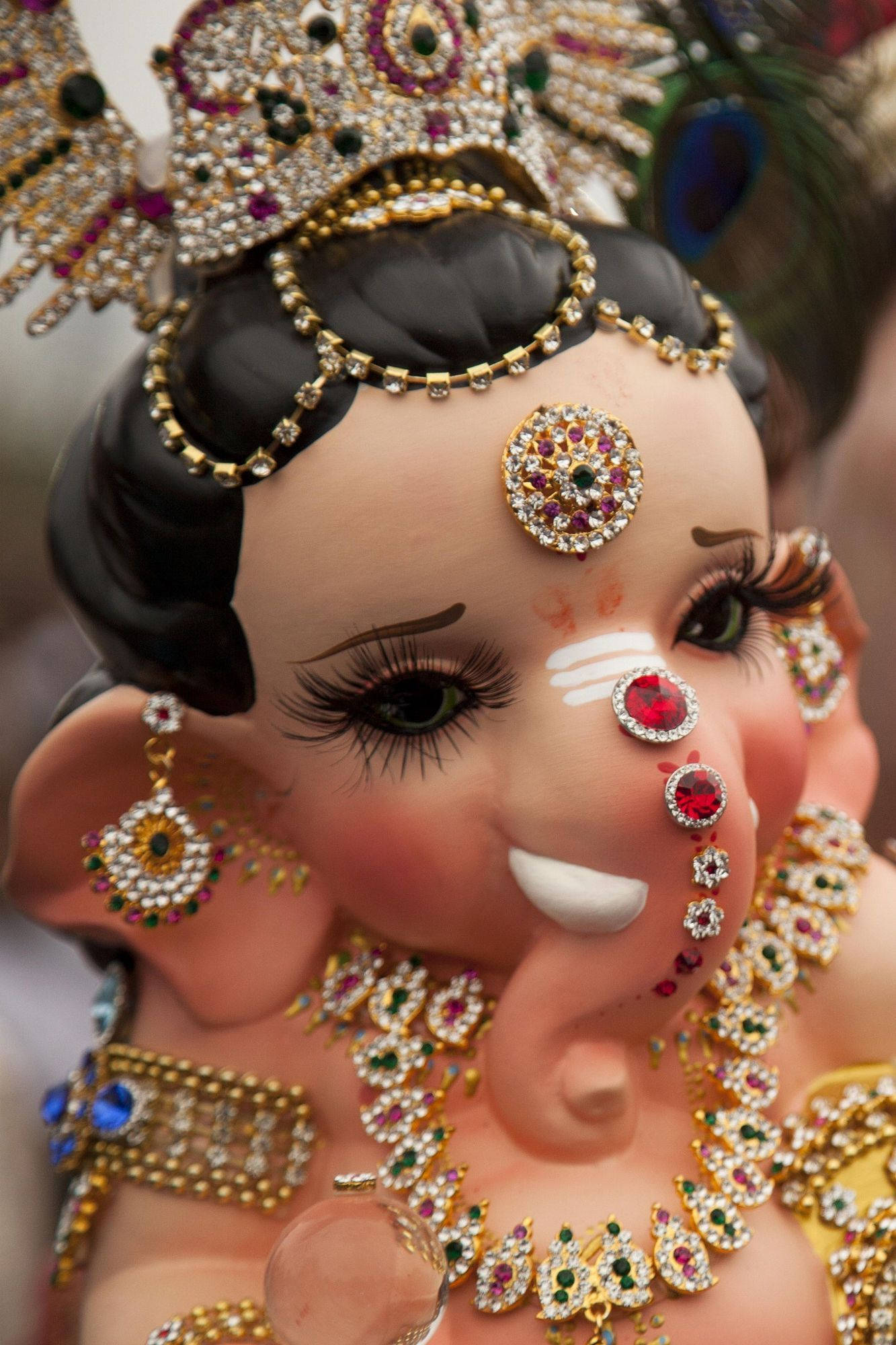 laxmi ganesh saraswati 桌布 壁紙 — 近距離拍攝一尊色彩鮮豔、鑲滿珠寶的印度教象頭神像，飾有金鏈和寶石。
