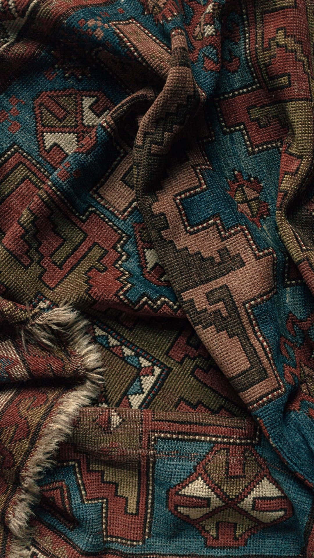 Carpet 桌布 壁紙 — 近距離拍攝一張質感豐富的部落風格地毯，帶有深青綠色、鏽色和米色調的幾何圖案。