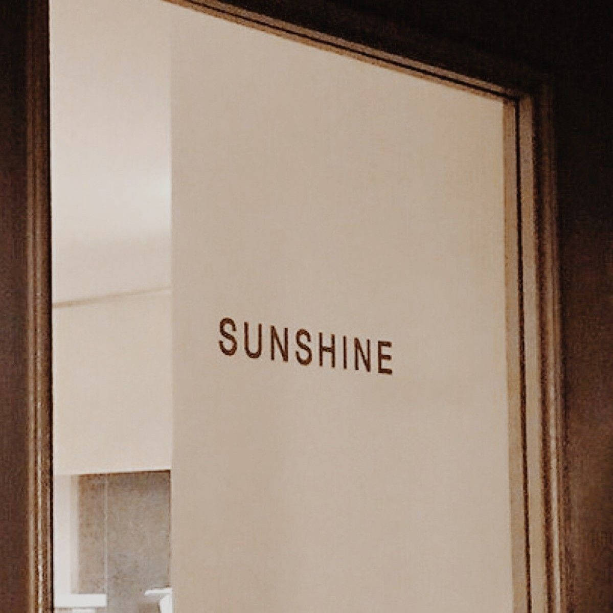 Tan 桌布 壁紙 — 近距離拍攝一扇磨砂玻璃門，上面用棕色字體刻有SUNSHINE字樣，並以深色木框鑲嵌。