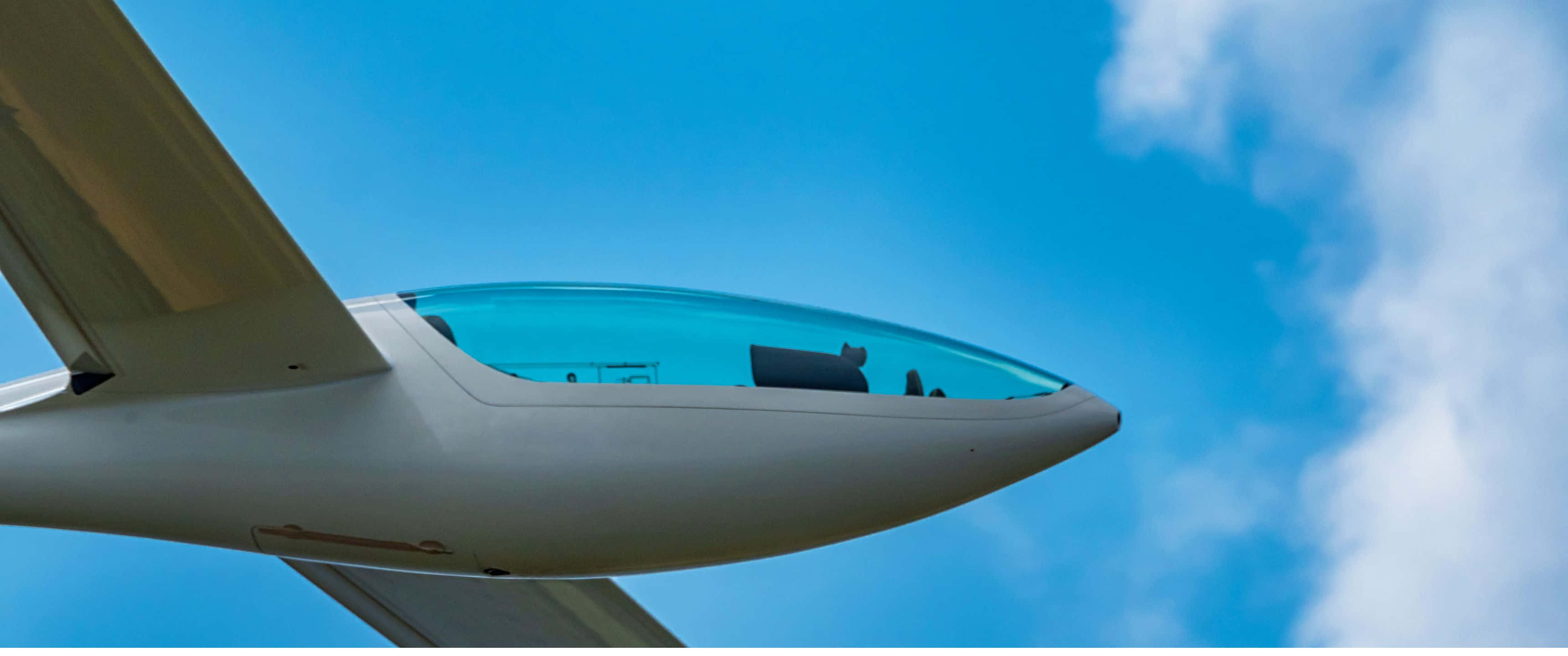 3440x1440p Small Planes 桌布 壁紙 — 近距離拍攝一架流線型白色滑翔機在湛藍天空與蓬鬆白雲中翱翔。