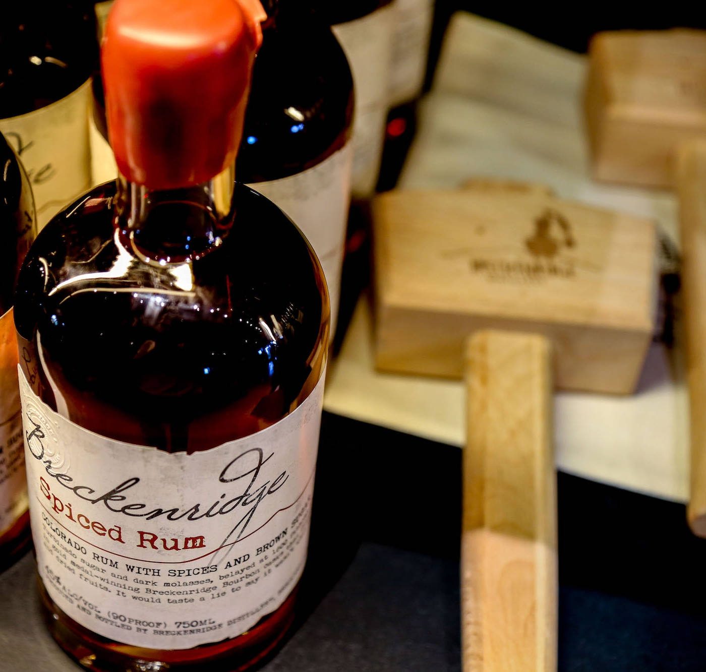 Drink 桌布 壁紙 — 近距離拍攝一瓶 Breckenridge Spiced Rum，紅色瓶蓋，背景有木盒。