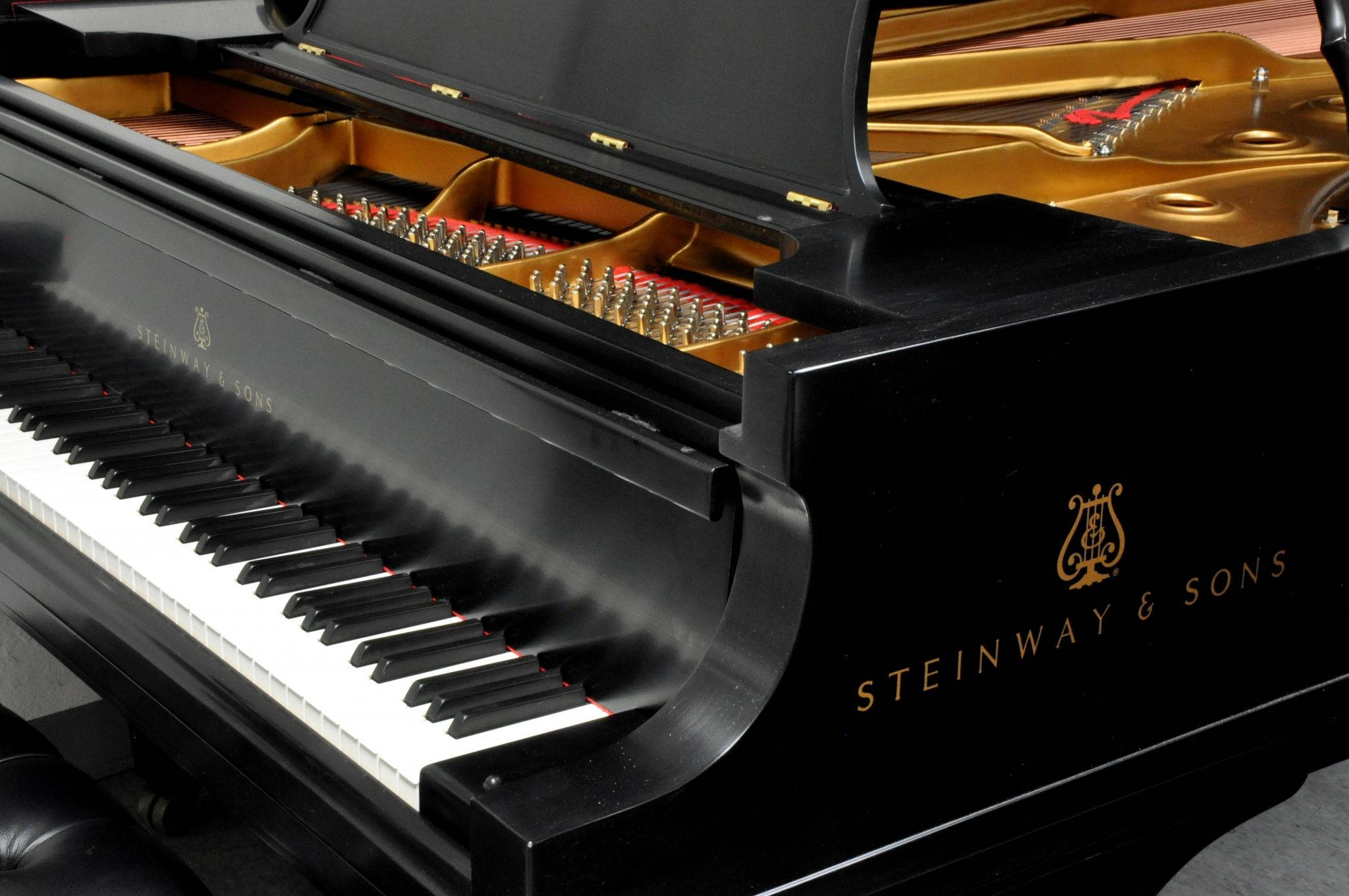 鋼琴 桌布 壁紙 — 近距離拍攝一輛亮黑色 Steinway & Sons 三角鋼琴，琴蓋打開，露出金色內部及精細的琴槌。
