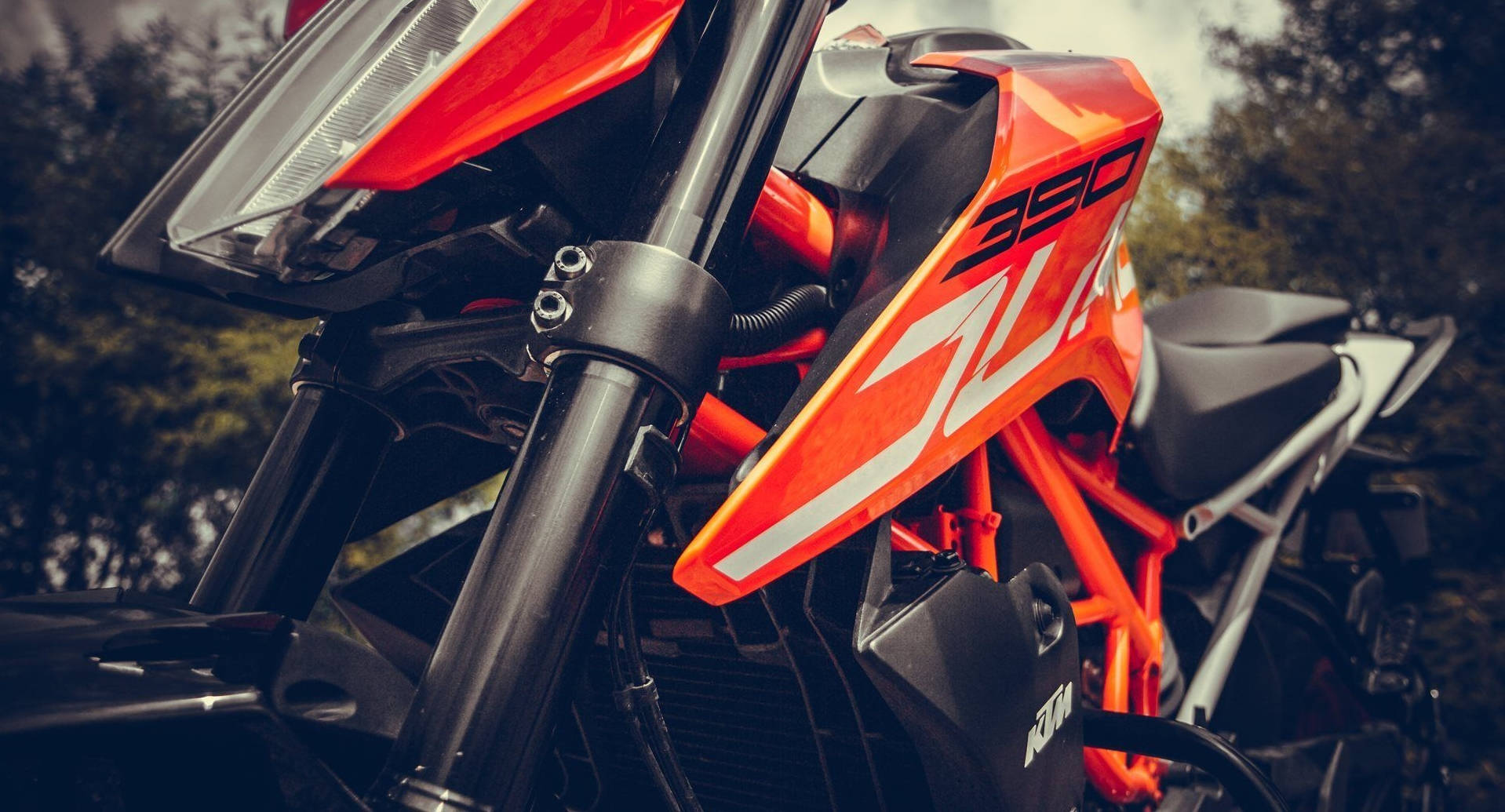 一輛鮮橙色KTM 390越野機車帶有黑色點綴，停放在森林中。 — 機車 壁紙