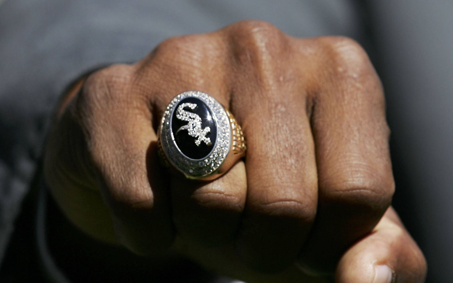 Chicago White Sox 桌布 壁紙 — 近距離拍攝一隻緊握的拳頭，自豪地展示一枚鑲有閃亮鑽石的芝加哥白襪隊冠軍戒指。
