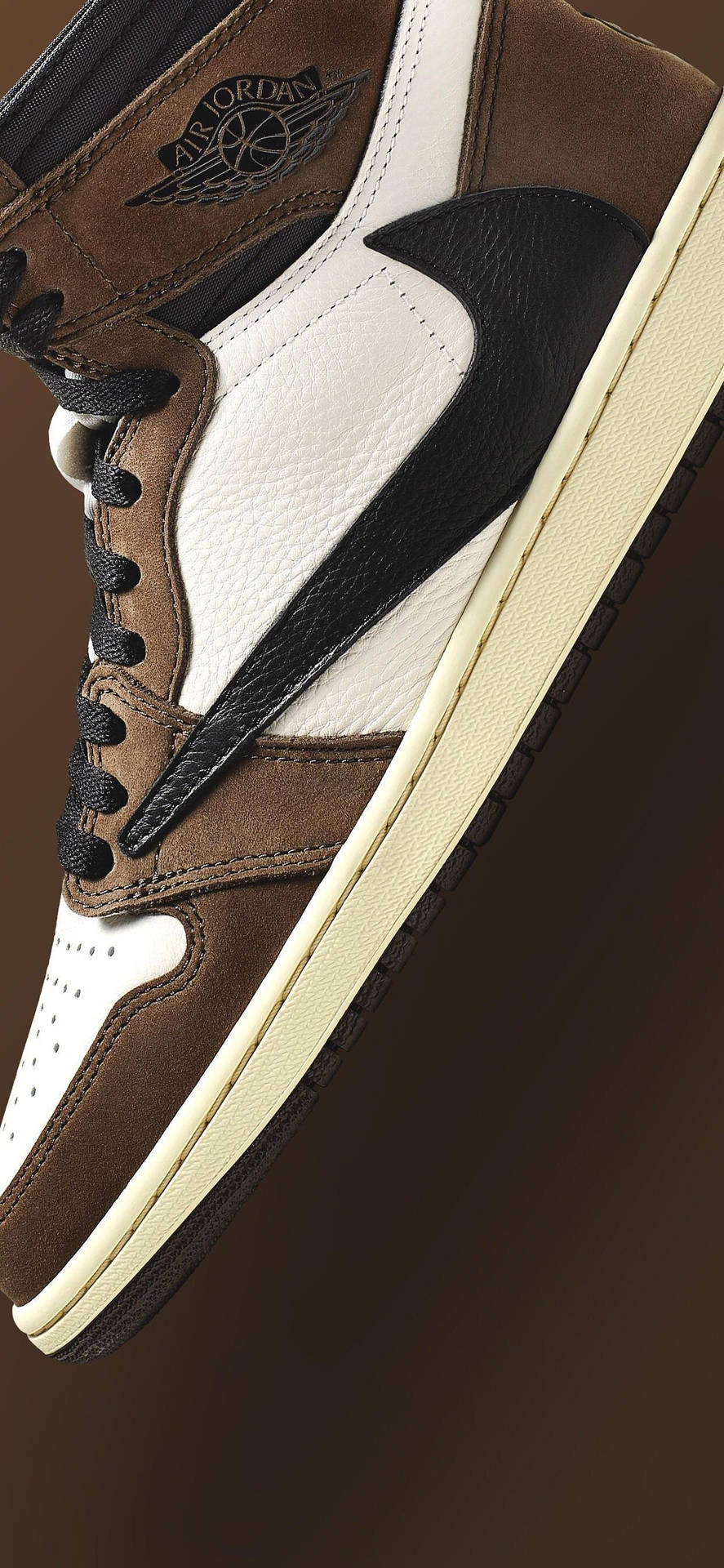 Travis Scott 桌布 壁紙 — 近距離拍攝一雙棕色、白色和黑色的 Air Jordan 運動鞋，配以奶油色鞋底，背景為深棕色。