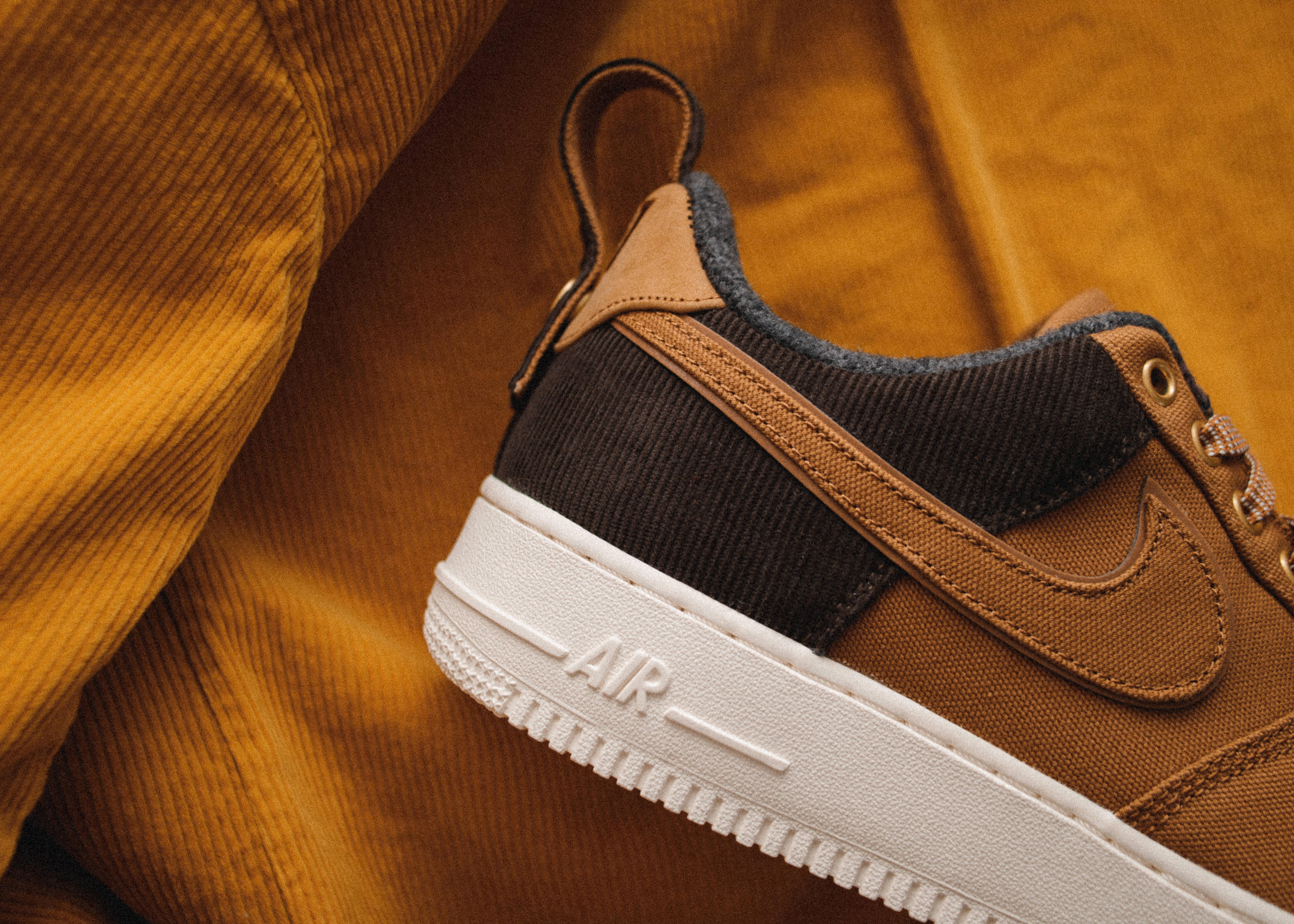 Shoe 桌布 壁紙 — 近距離拍攝一雙棕色Nike Air運動鞋，白色鞋底，置於芥末黃色燈芯絨布料上。