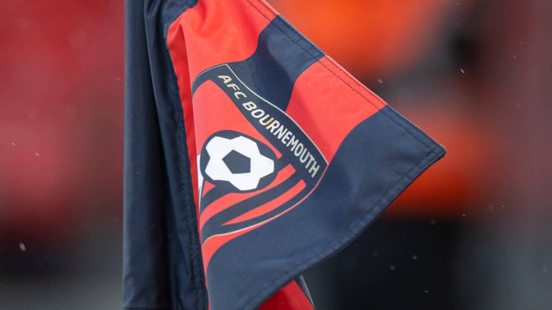 足球 桌布 壁紙 — 近距離拍攝一面紅色和深藍色的 AFC Bournemouth 旗幟，帶有足球標誌，隨風飄揚。