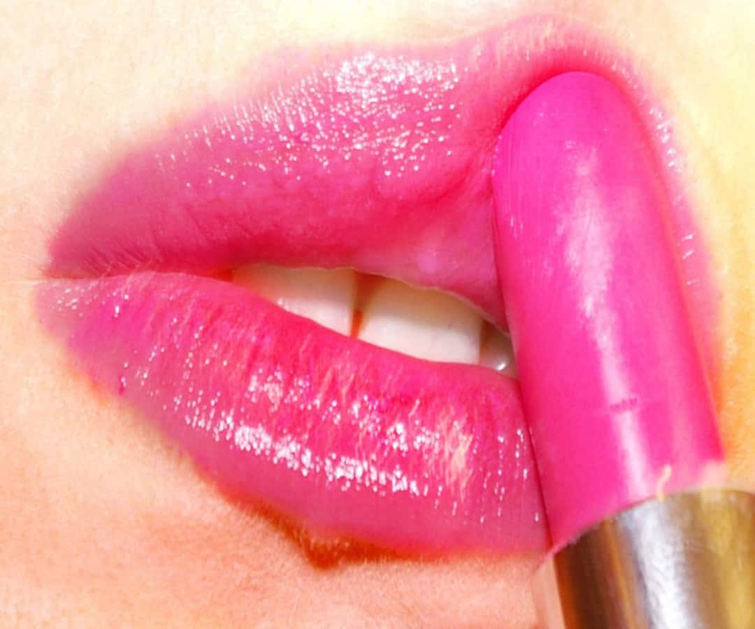 Pink Lipstick 桌布 壁紙 — 近距離拍攝亮粉紅色嘴唇，正在塗抹相配的粉紅色唇膏管。