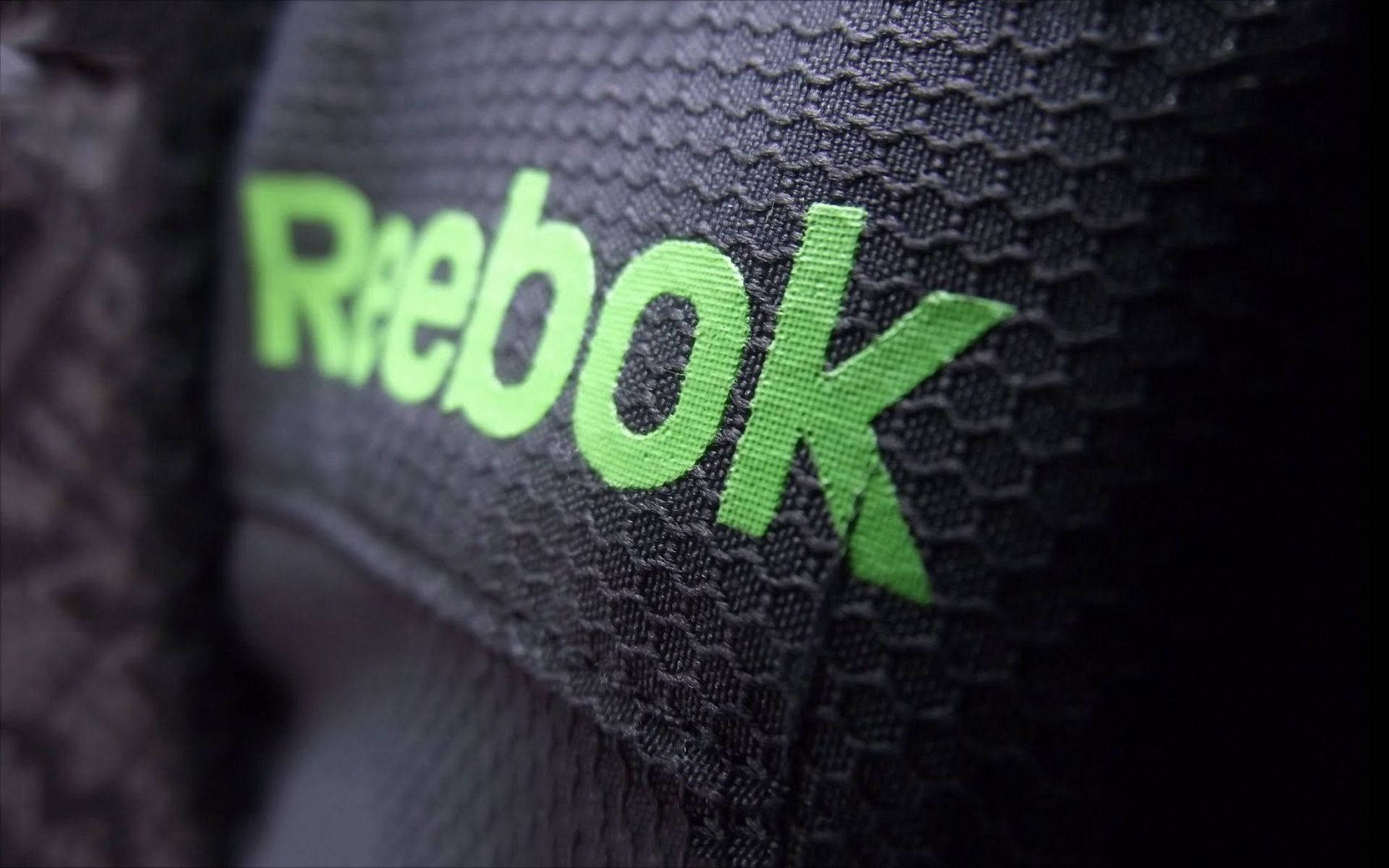 Reebok 桌布 壁紙 — 近距離拍攝亮綠色Reebok標誌縫在紋理黑色運動布料上，景深較淺。