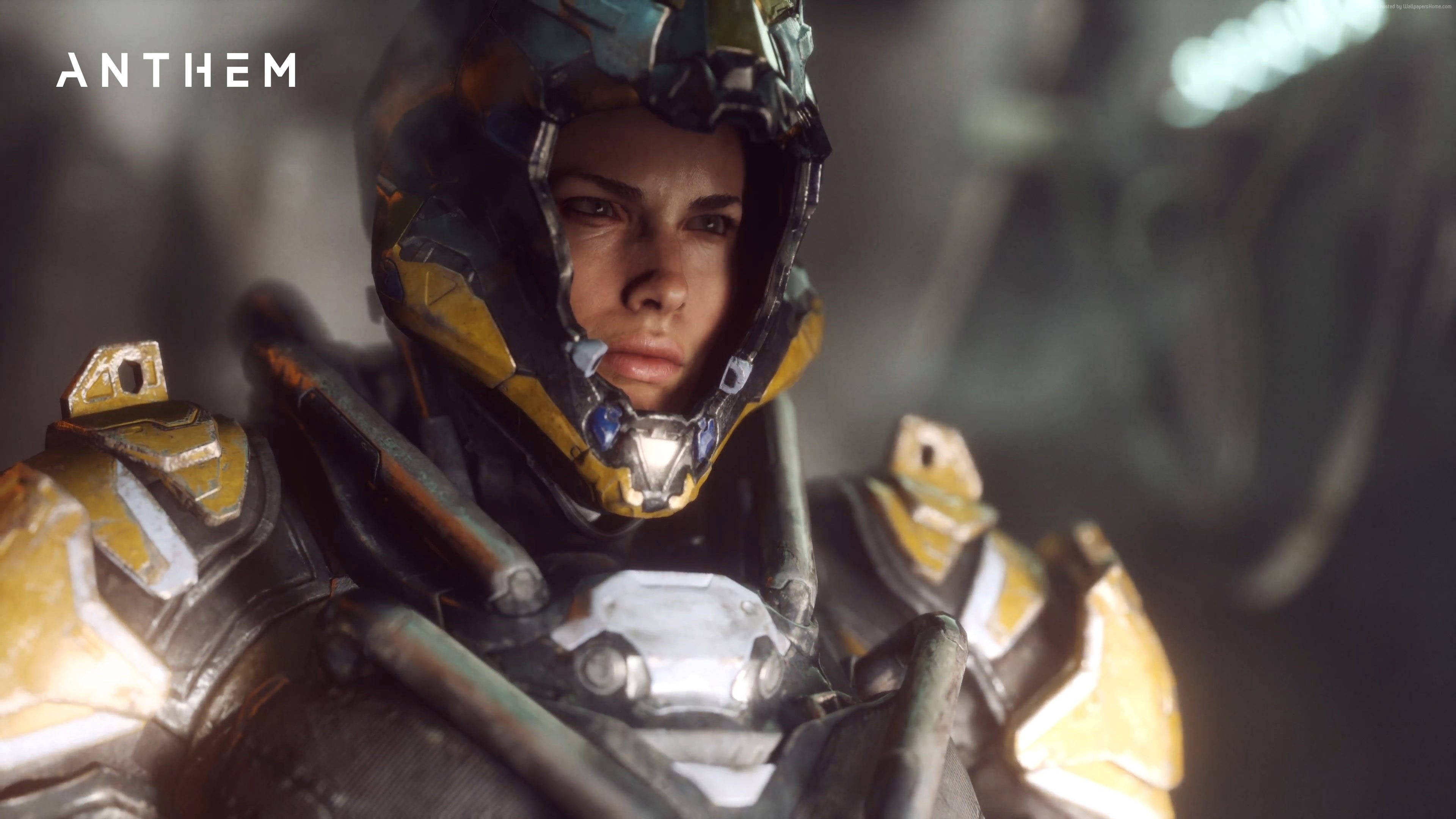 桌布 壁紙 — 近距離拍攝來自 Anthem 的堅定裝甲戰士，配備發光的黃色和黑色裝備，背景是模糊的工業場景。