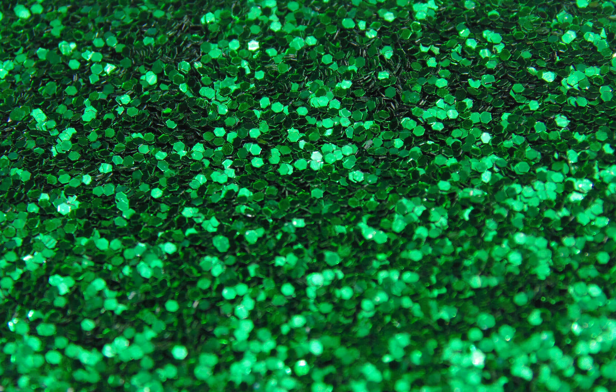 Green Glitter 桌布 壁紙 — 近距離拍攝充滿活力的綠色六角形亮粉粒子在明亮光線下閃閃發光。