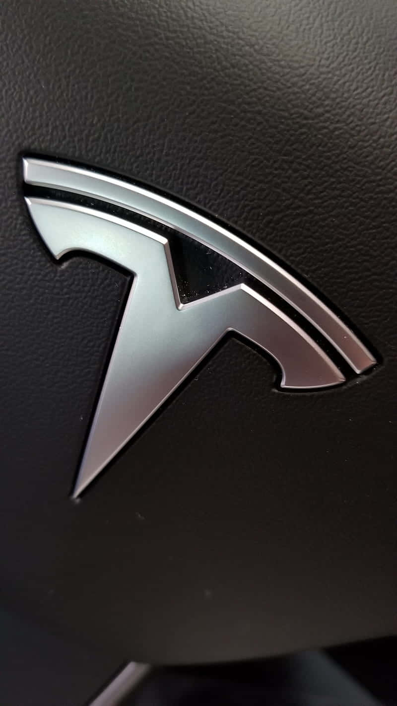桌布 壁紙 — 近距離拍攝嵌入在紋理黑色皮革內飾中的時尚銀色 Tesla 標誌。