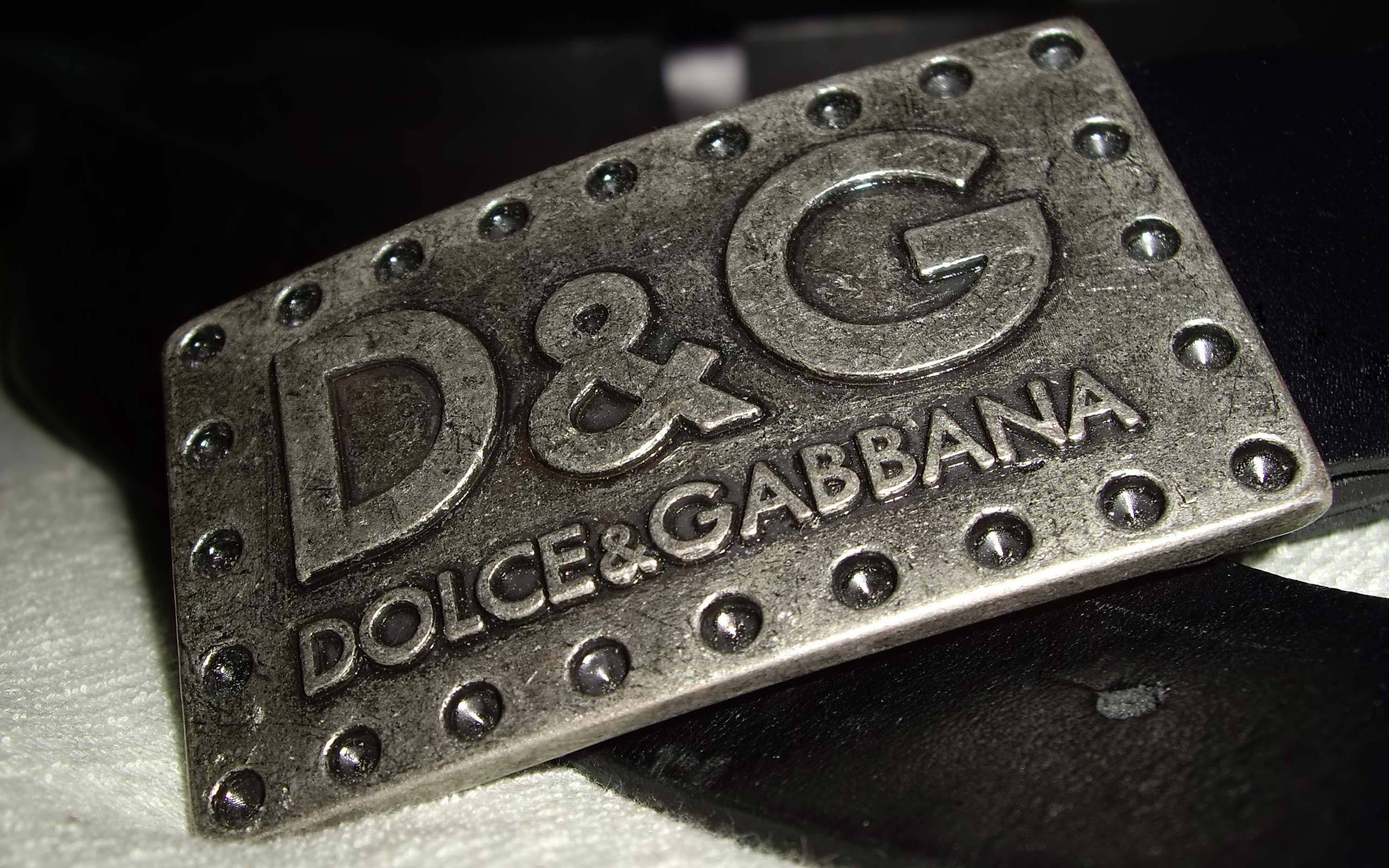 黑色 桌布 壁紙 — 近距離拍攝帶有鉚釘的紋理銀色 Dolce & Gabbana 皮帶扣，放置在黑色皮革和白色布料上。