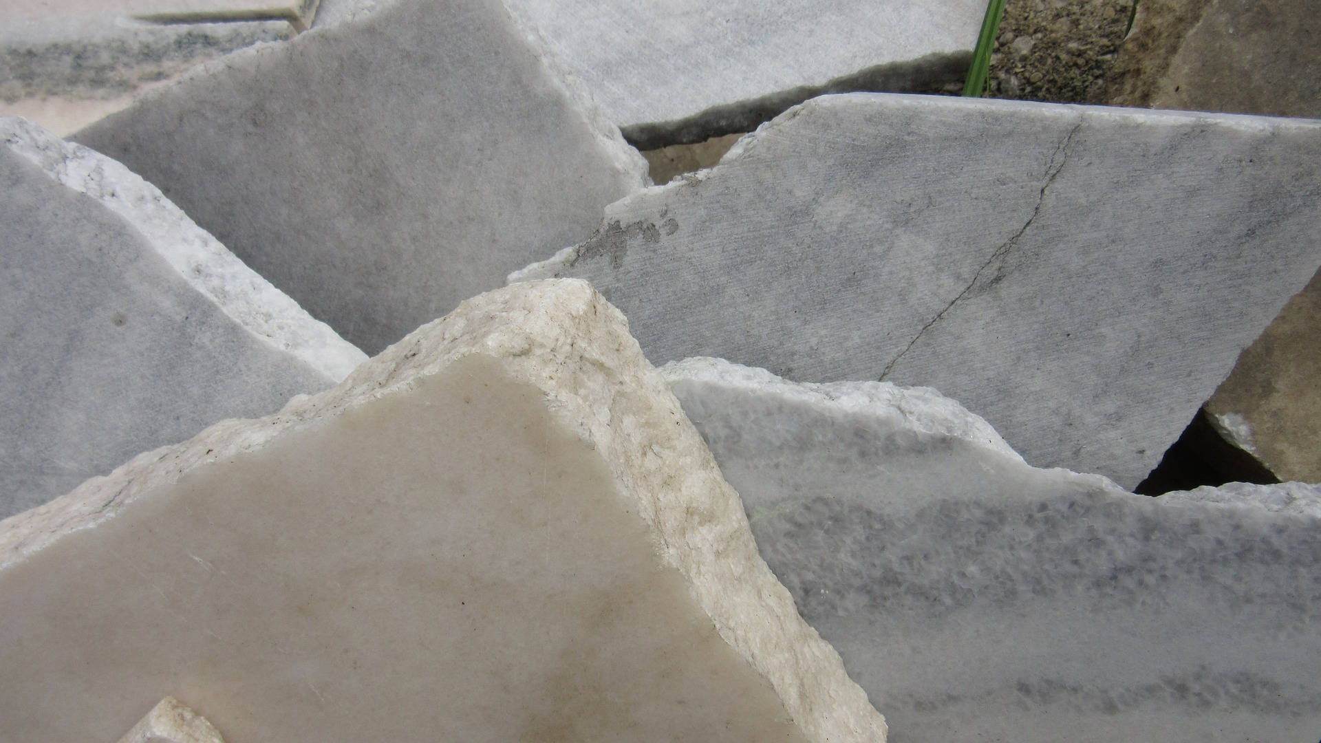 Marble Desktop 桌布 壁紙 — 近距離拍攝採石場中堆疊的粗糙切割灰色大理石石板，帶有可見紋理和缺角邊緣。